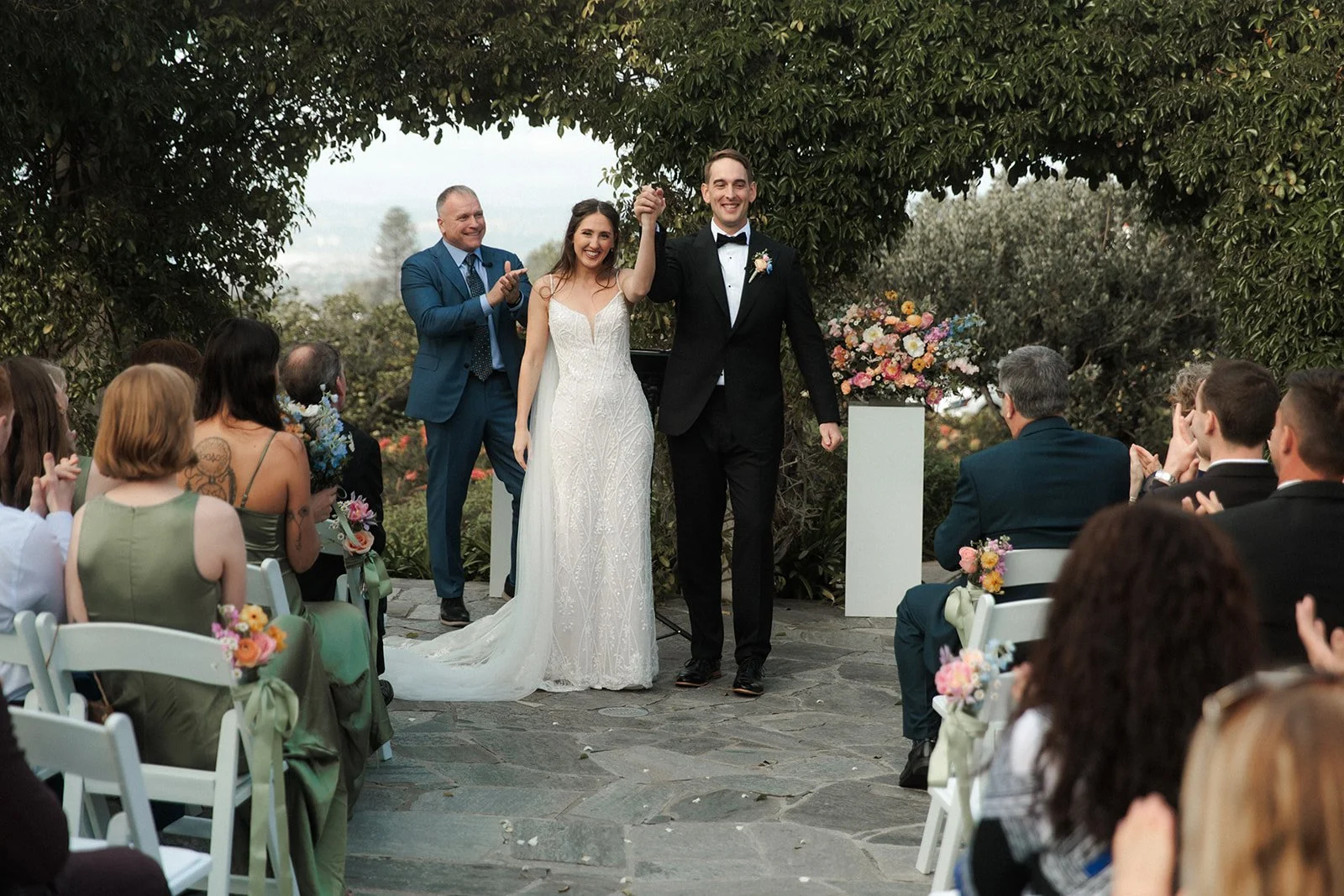 San Diego couple celebrates their wedding at The Thursday Club in Point Loma. Guests cheer while the couple smiles and holds hands.