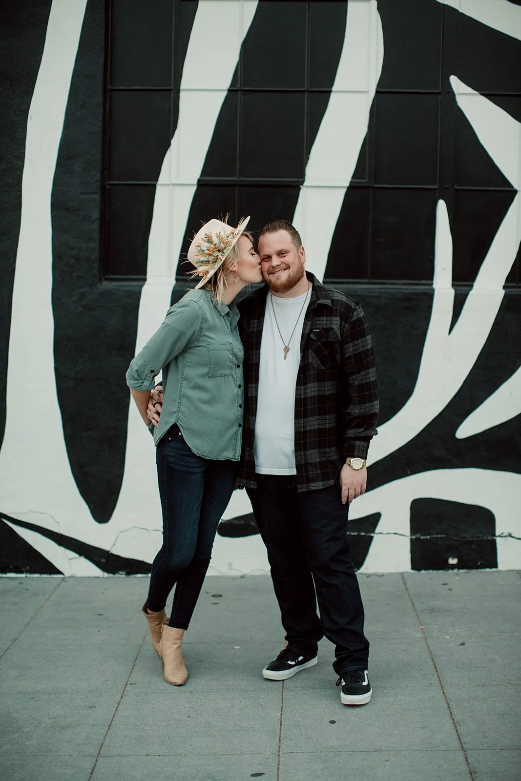 Bride to be playfully kisses her fianceé during an urban San Diego engagement photo session in Little Italy.