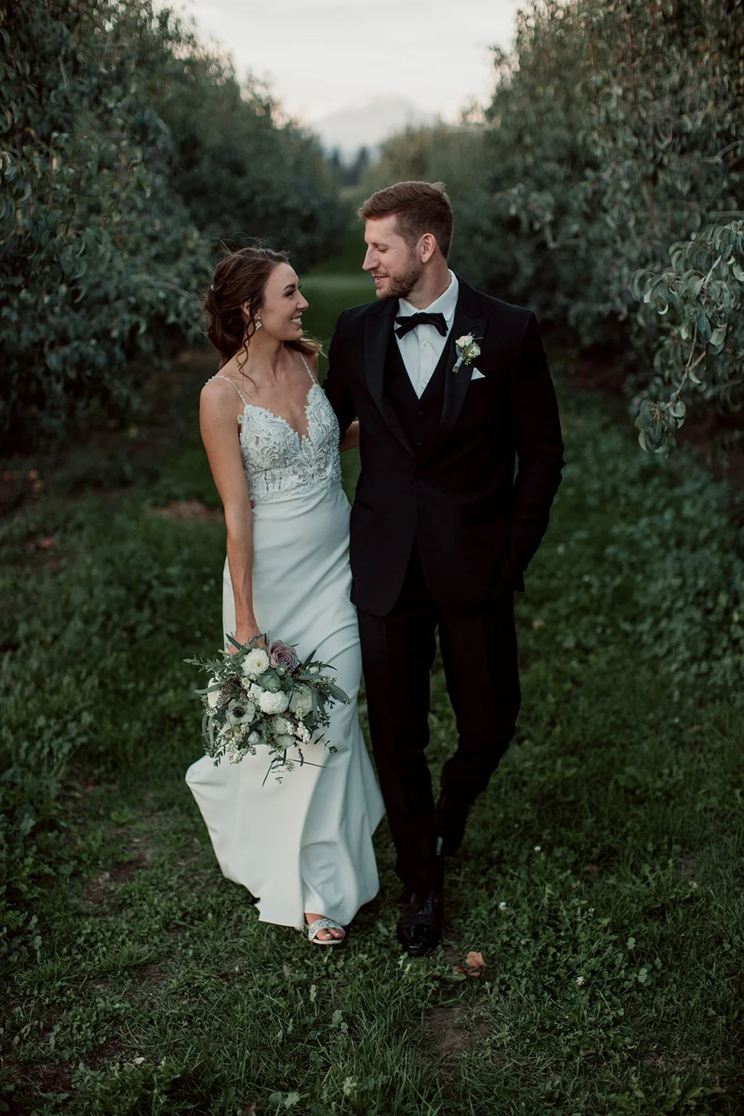 Bride and groom walk in an orchard at their San Diego wedding. 