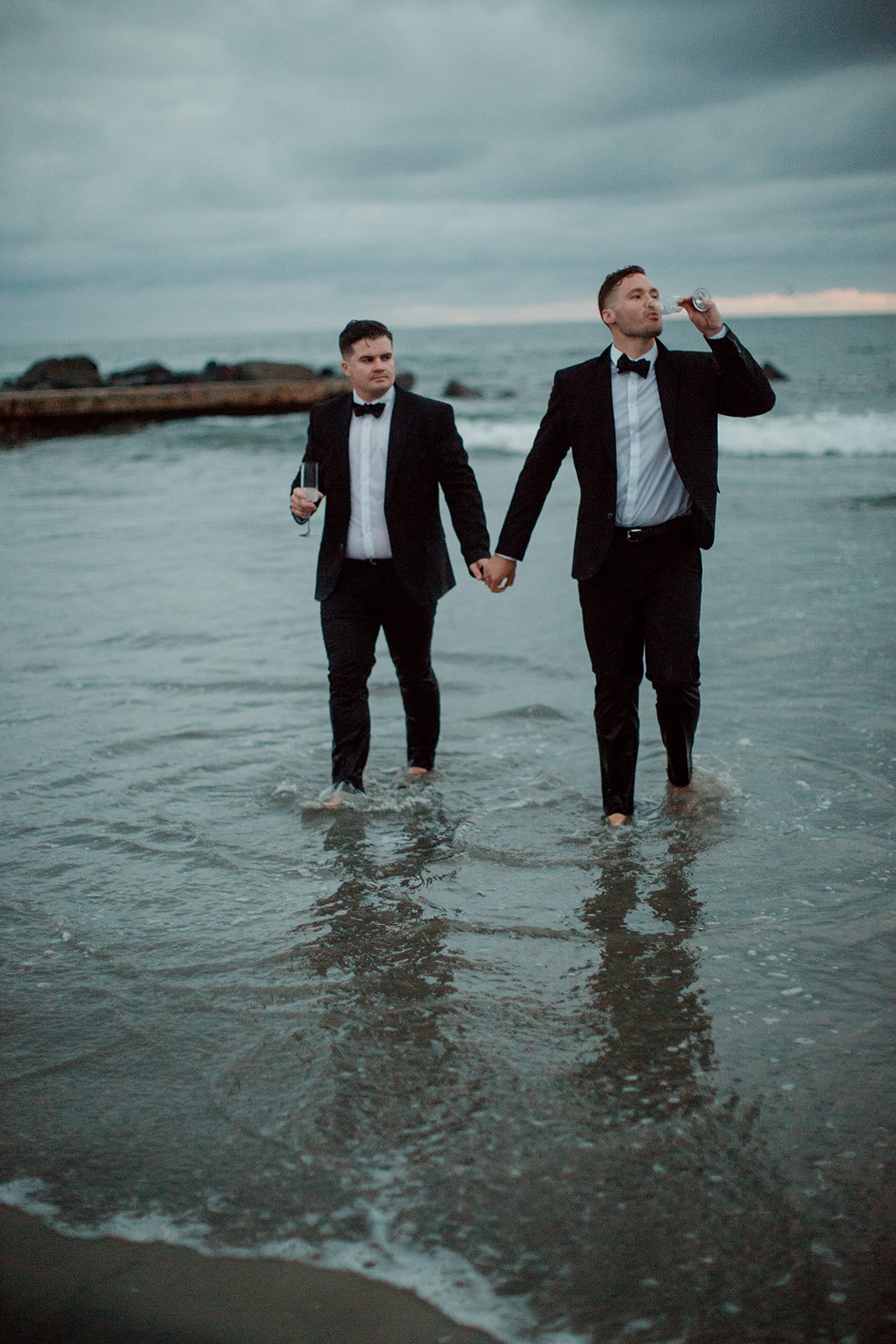 San Diego sunset engagement photos of a couple holding hands and drinking champagne.