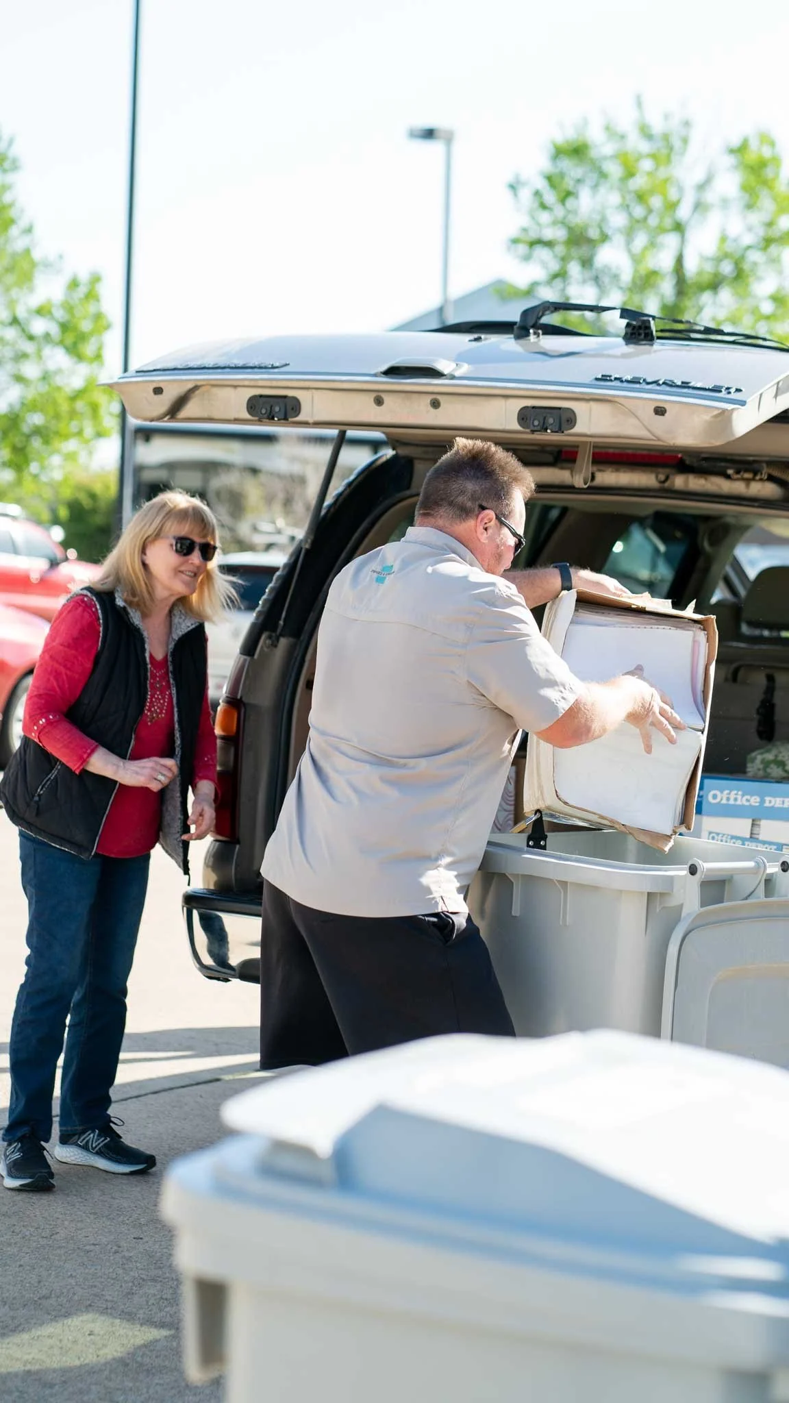 Man emptying box of paper into shred bin at free shredding event in Arkansas