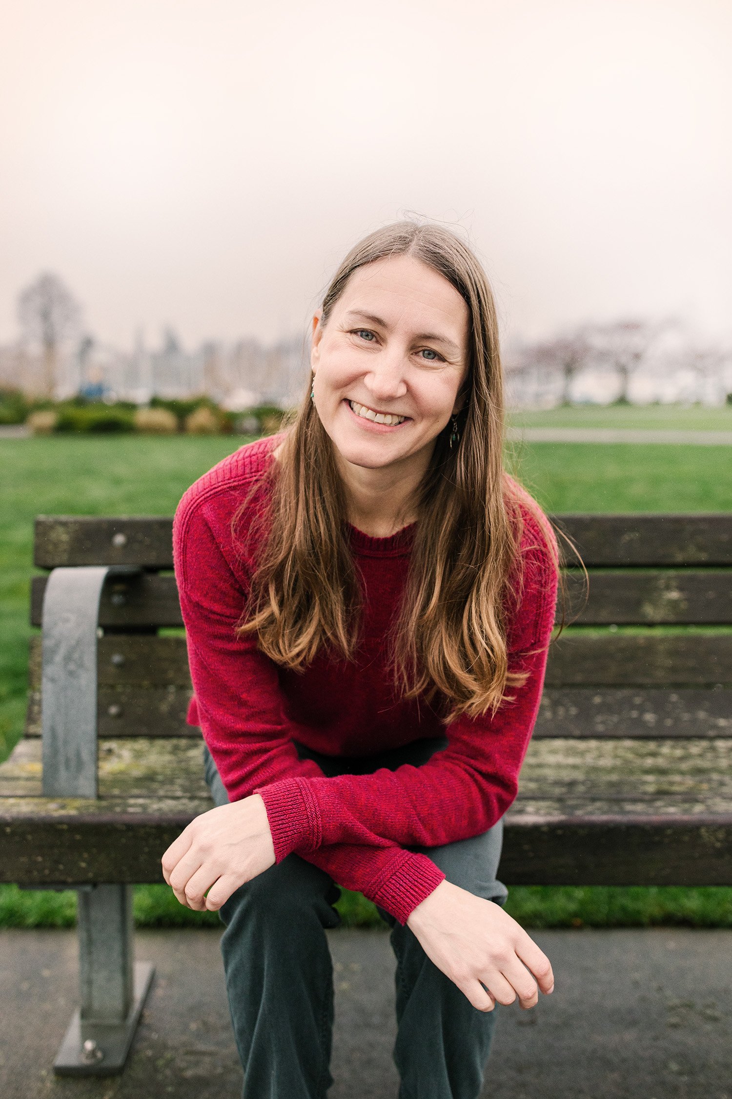 Beth on a bench smiling in a red sweater