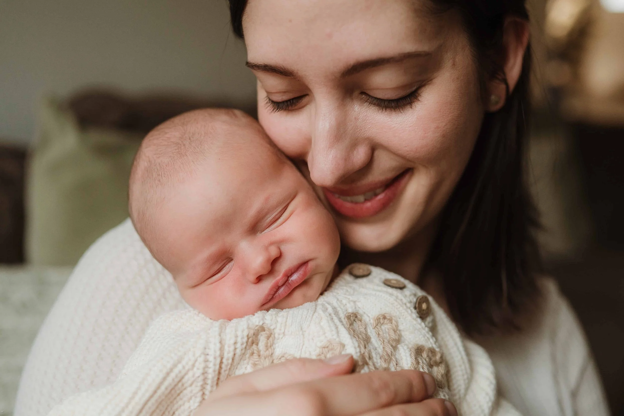 newborn baby being held by his mother who has a smile on her face