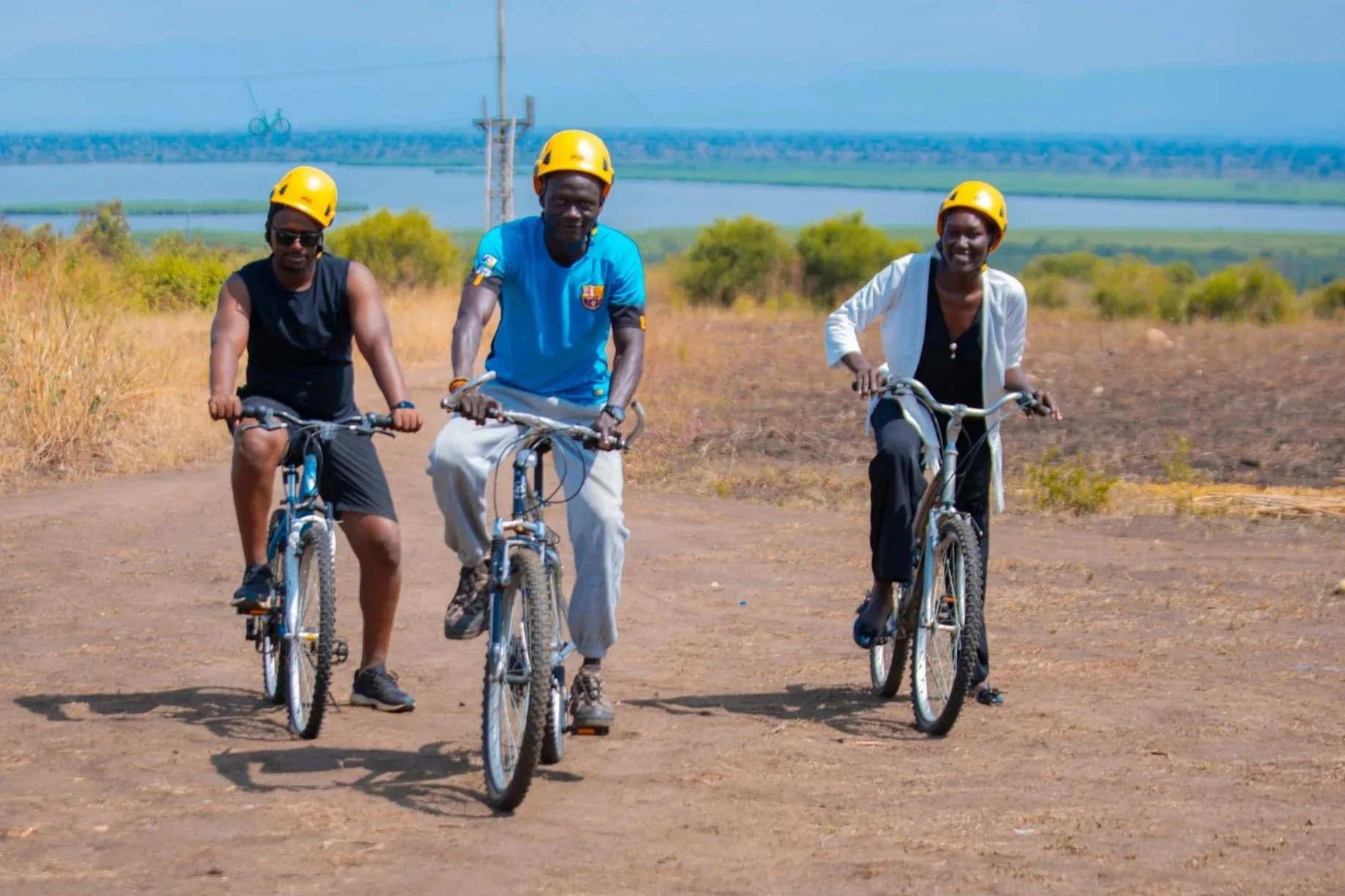 Three cyclists smiling for the camera and riding on dirt roads