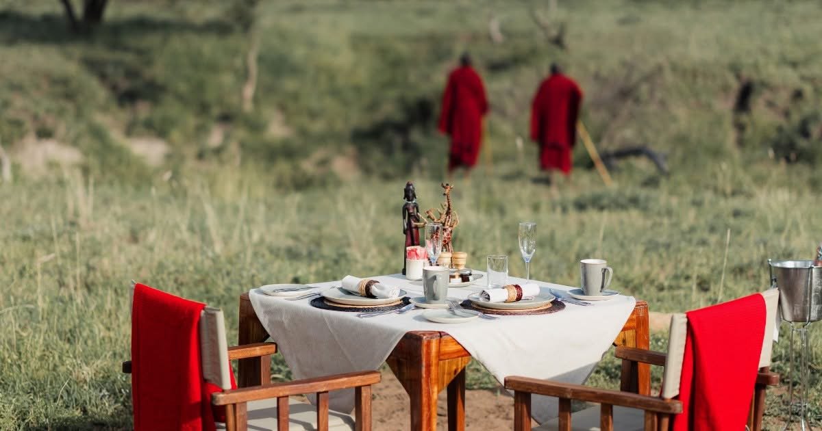 Beautiful table set for two outdoors with local tribesmen in the distant background