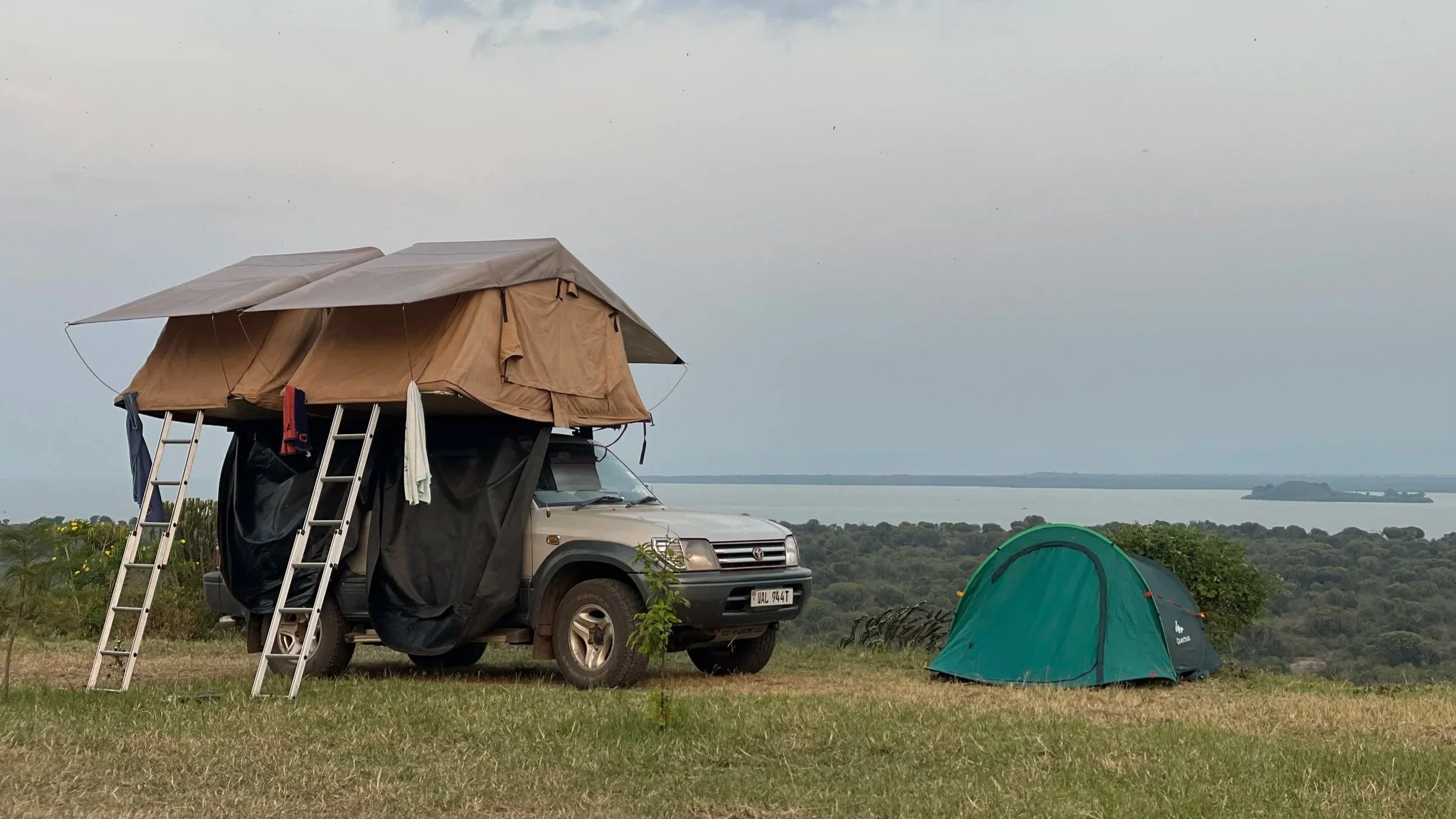 Dual tent camping setup on top of a vehicle wiht another tent pitched on the ground