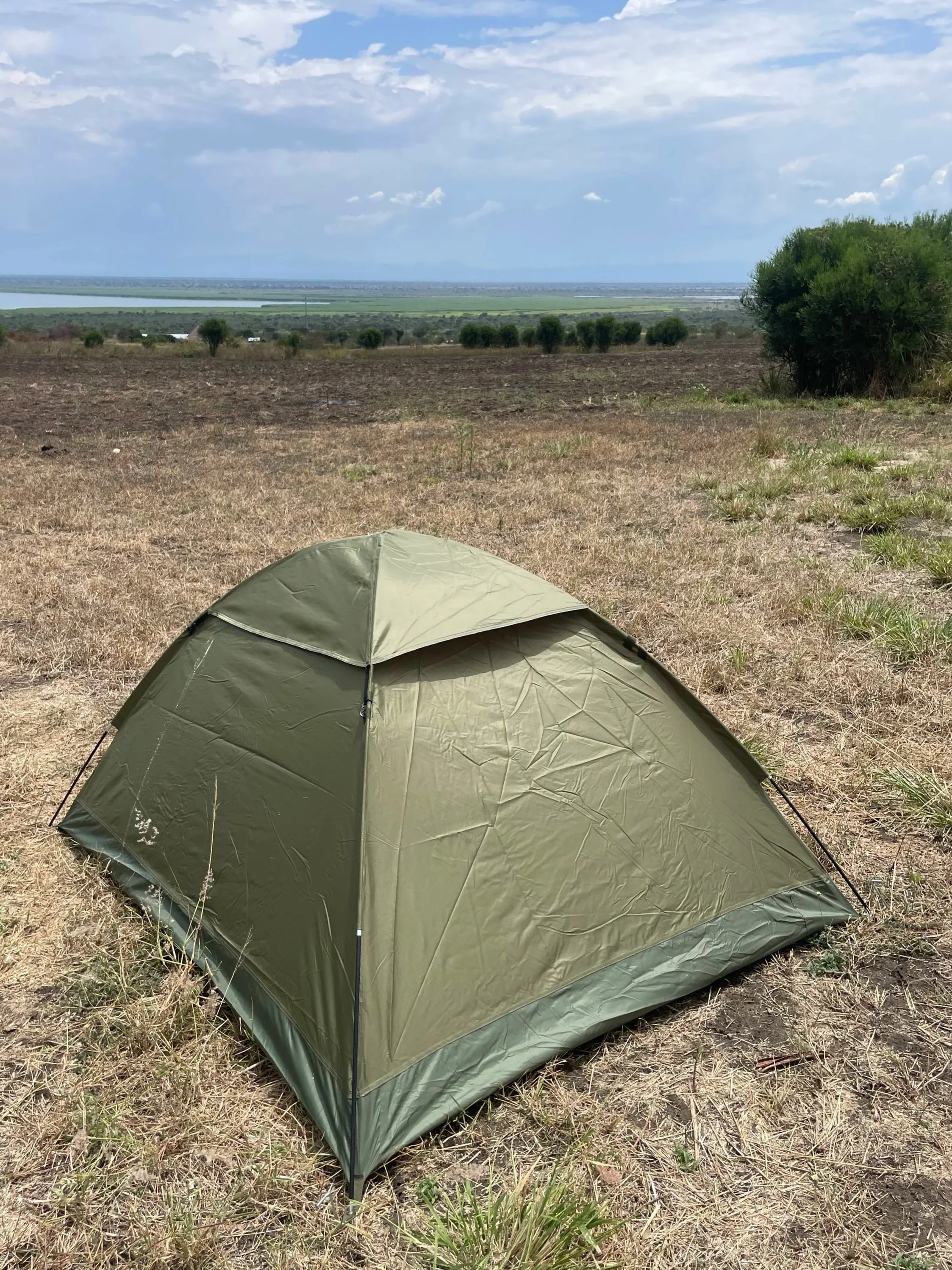 A green camping tent set up on the ground
