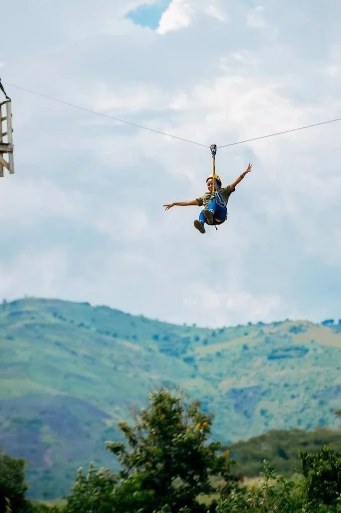 A woman on a zip line with her arms spread out