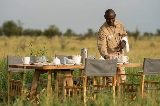 Server setting the table for an outdoor dining experience
