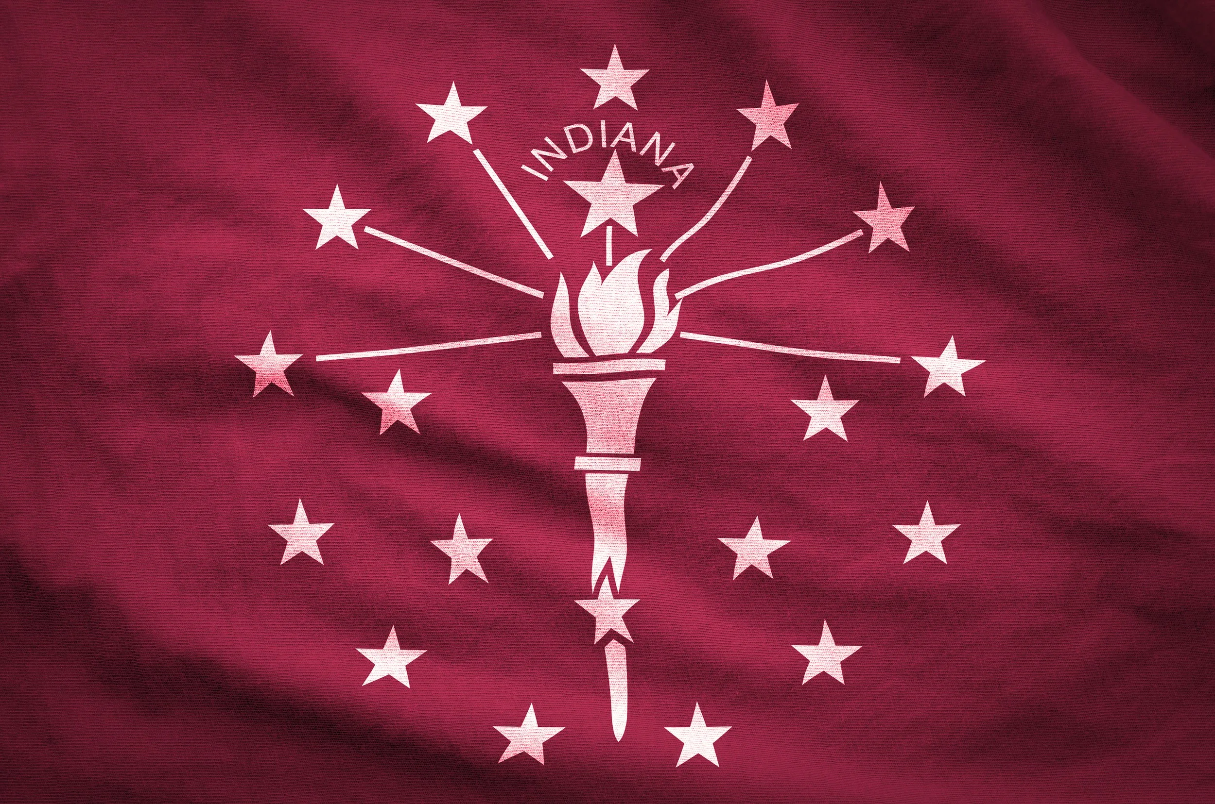 Close-up of the Indiana state flag featuring a torch and stars on a red background.