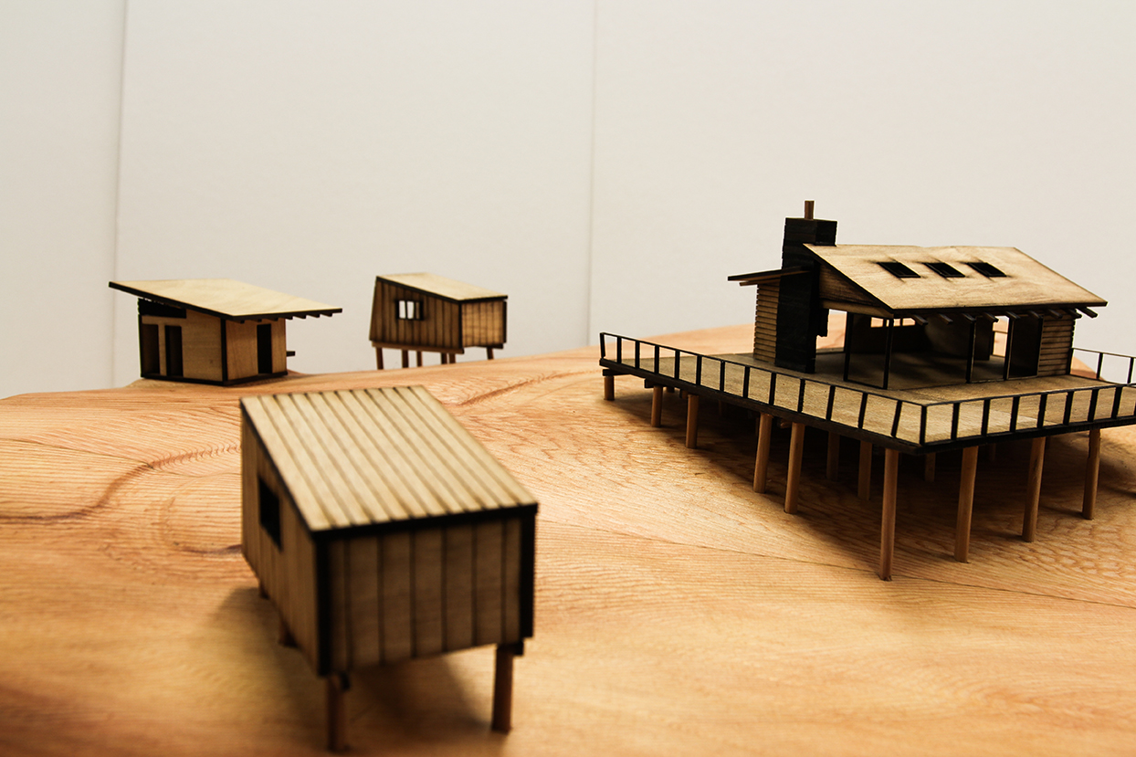 Small wooden model of home on raised platform.