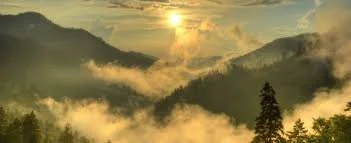 Mountain landscape at sunrise with clouds and fog.