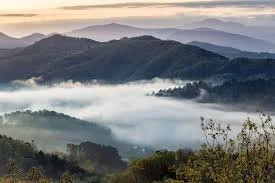 Scenic view of misty mountains and rolling hills at sunrise or sunset.