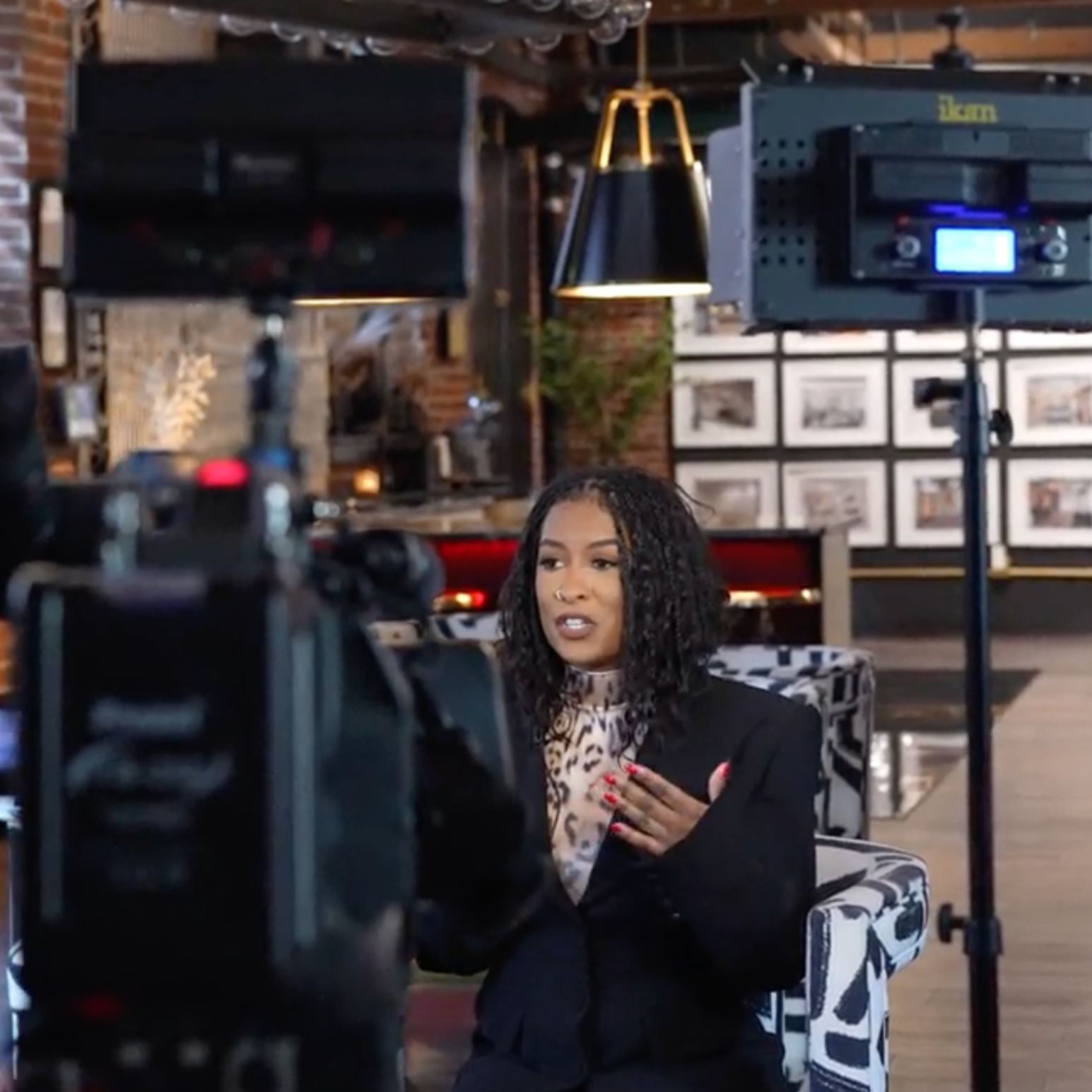  Principal Designer Dominique Calhoun during her interview with 6ABC, speaking confidently on camera in a stylish, art-filled setting. Surrounded by professional lighting and production equipment, Dominique brings her signature poise and presence as 