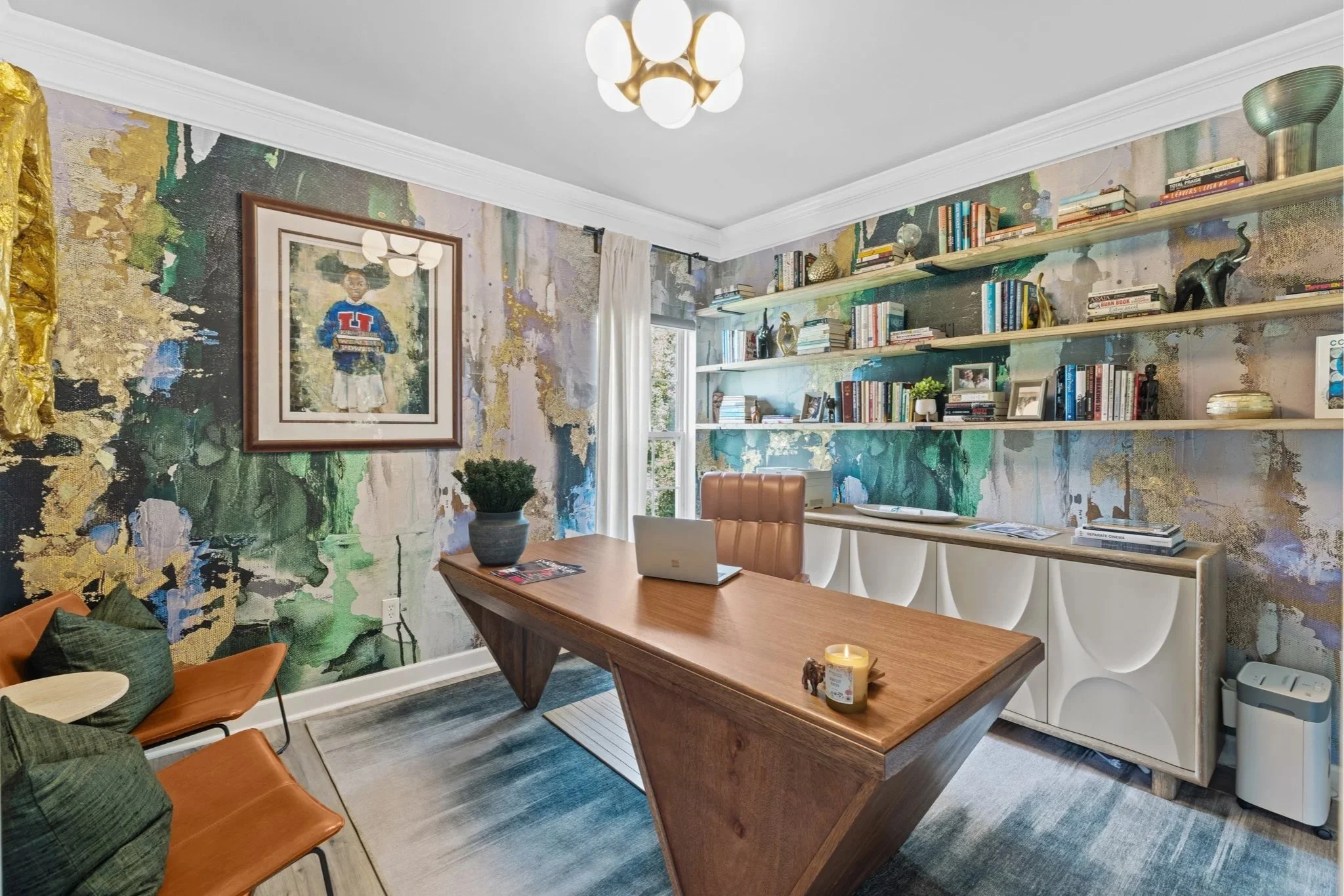 This Remix Living designed home office is a bold, modern, and art-forward workspace that blends creativity with function. A dramatic abstract wallcovering in rich greens, blues, and golds sets the tone, creating an inspiring backdrop for the sculptur