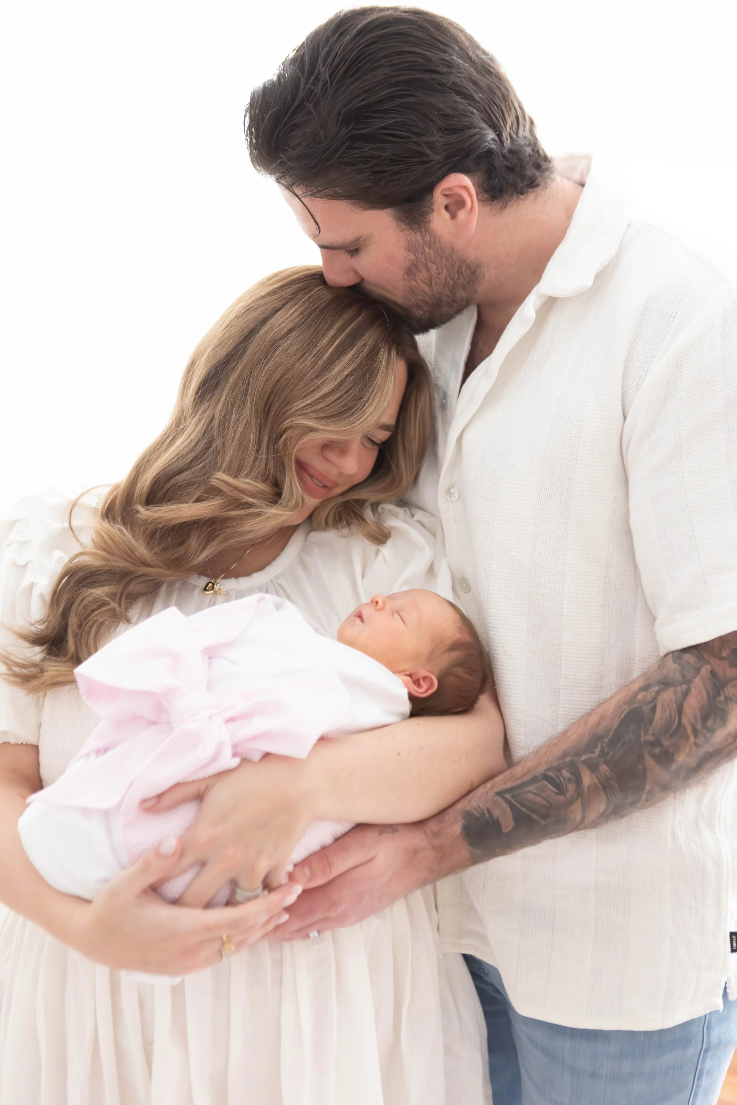 Baby with light skin and red hair sleeping, wrapped in a blue blanket against a white background.