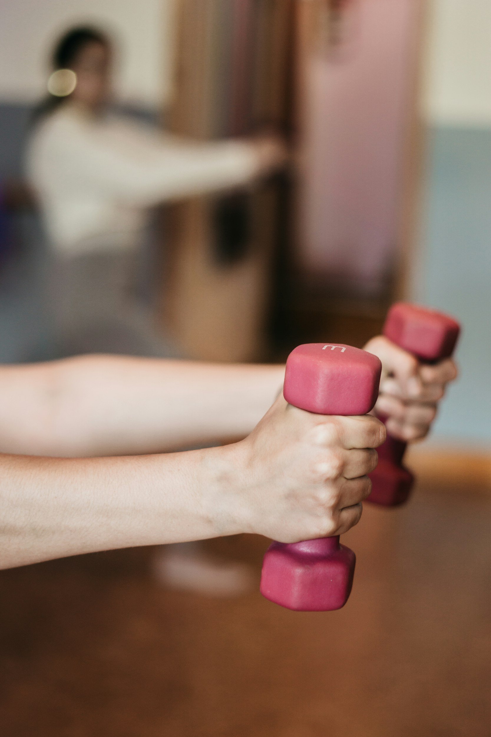Person holding pink dumbbells during workout session.