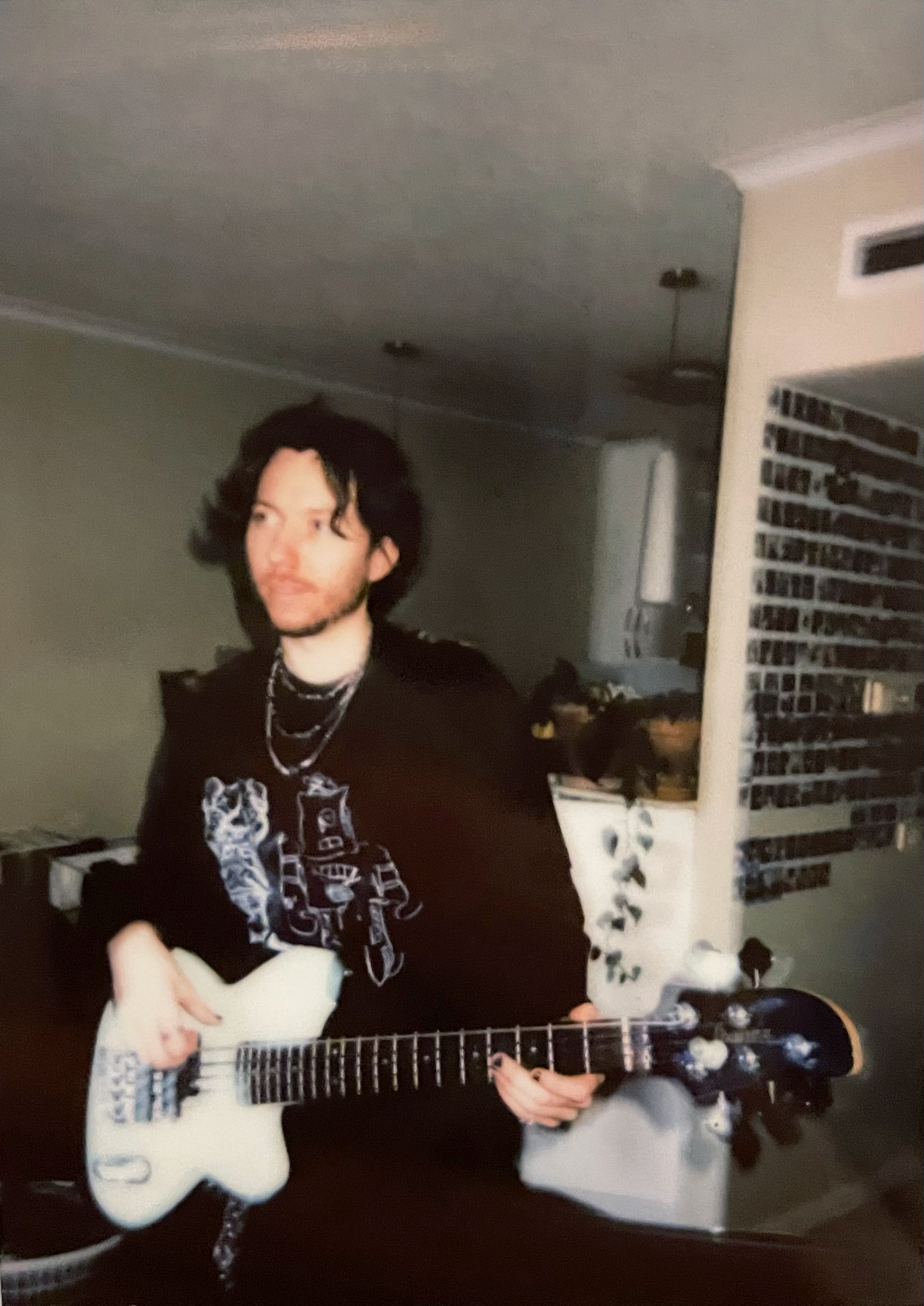 Brodie Travers smiling and making a peace sign, wearing a patterned shirt, standing indoors.