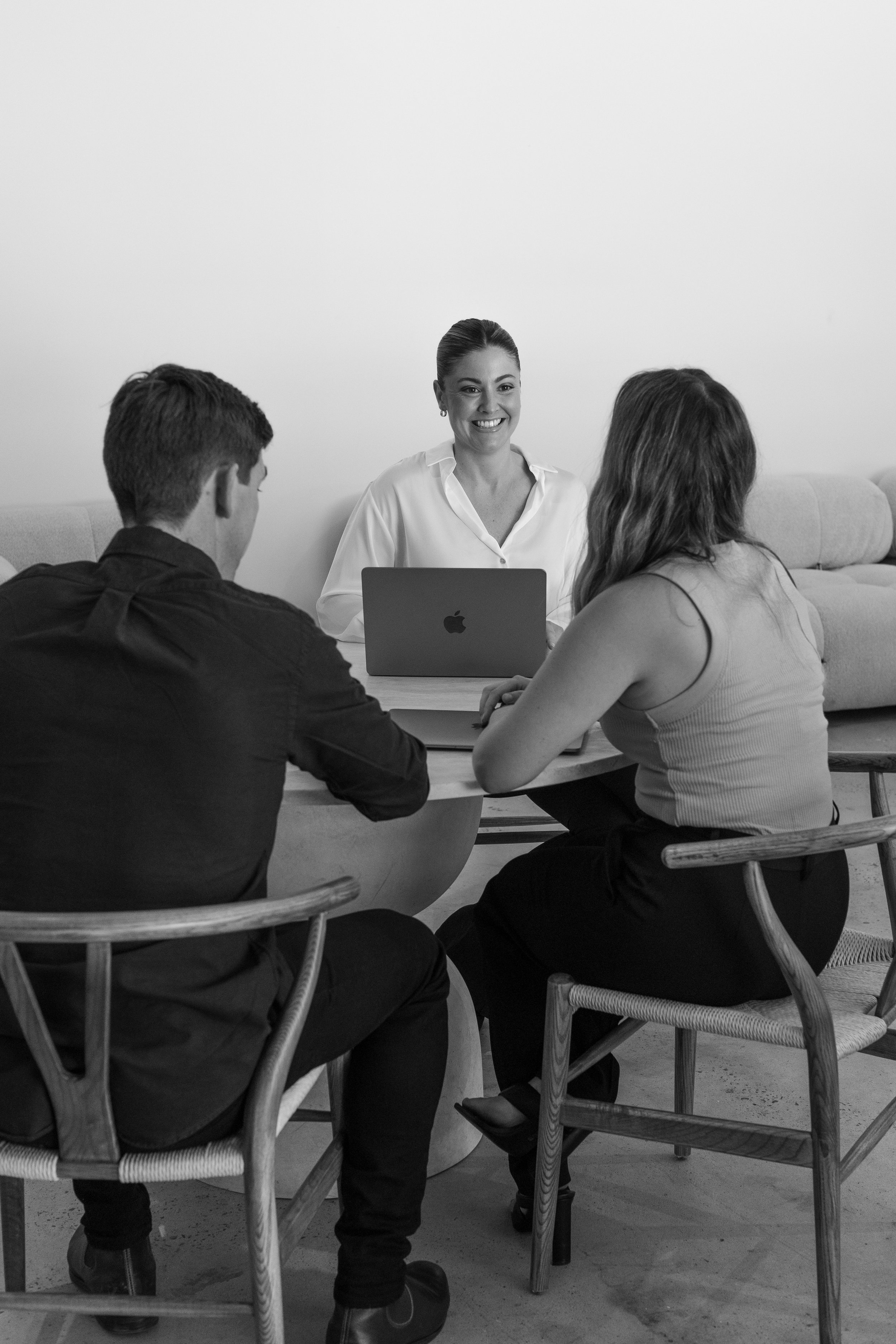 Jarrah Wallace - Kajabi Systems & Automations Partner.  Four people sitting around a table in a meeting room, with a woman smiling at the camera in front of a laptop.