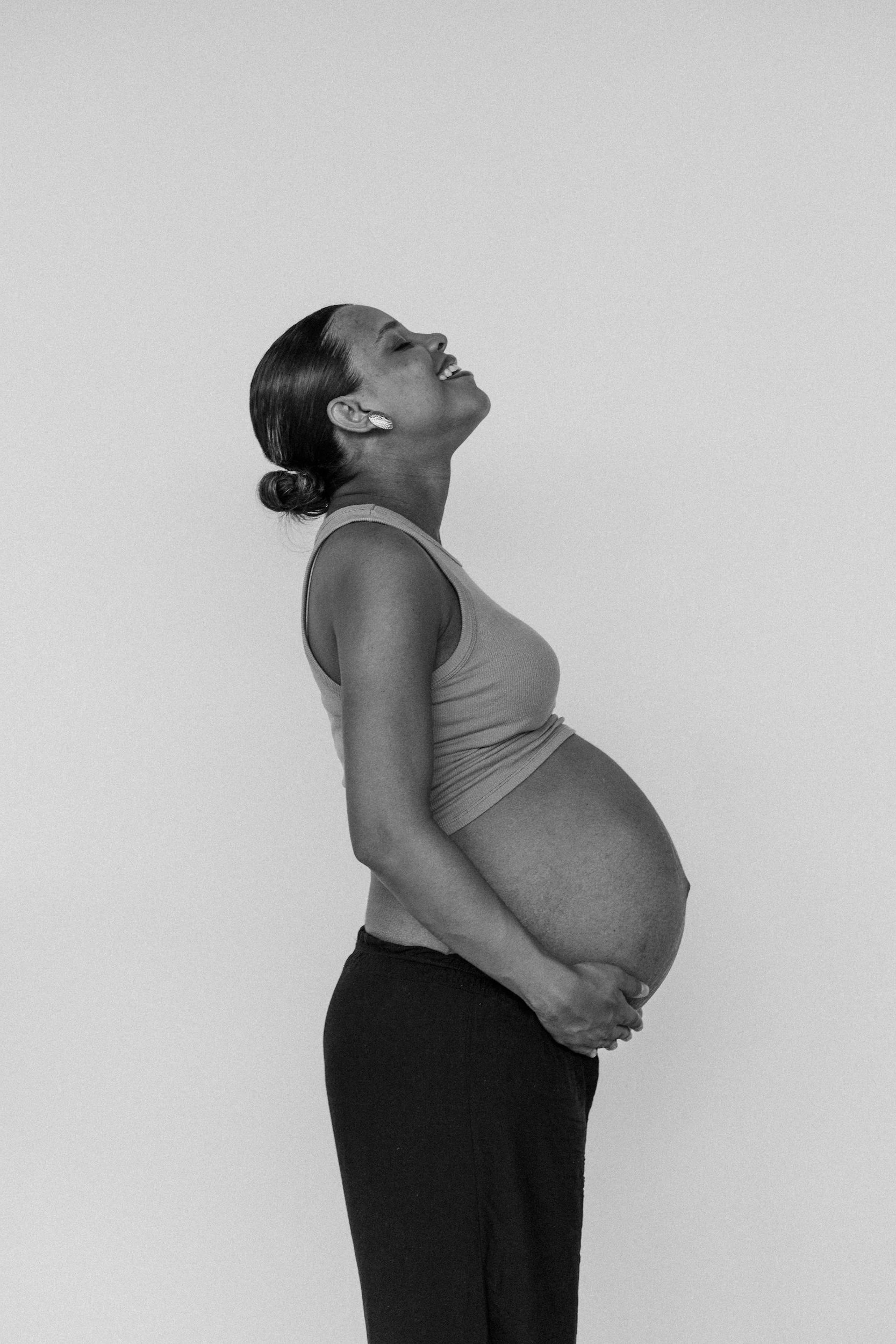 Pregnant Woman holding her belly and smiling