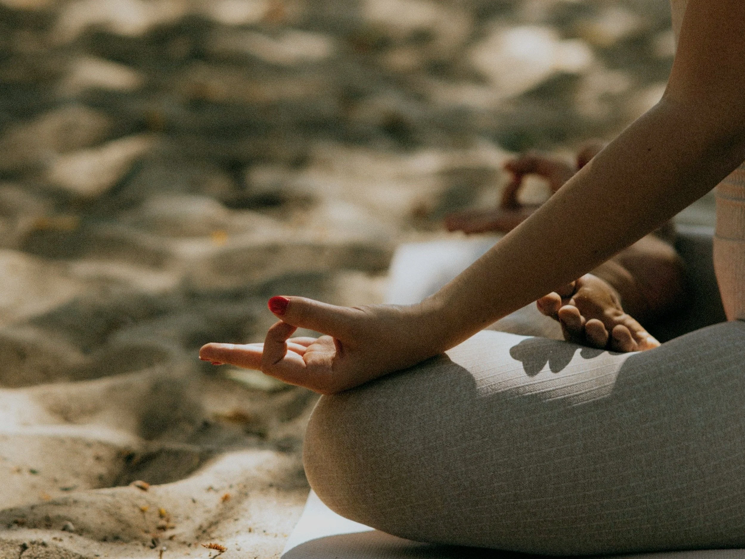arms and legs catured in meditation pose on the beach in warm light.
