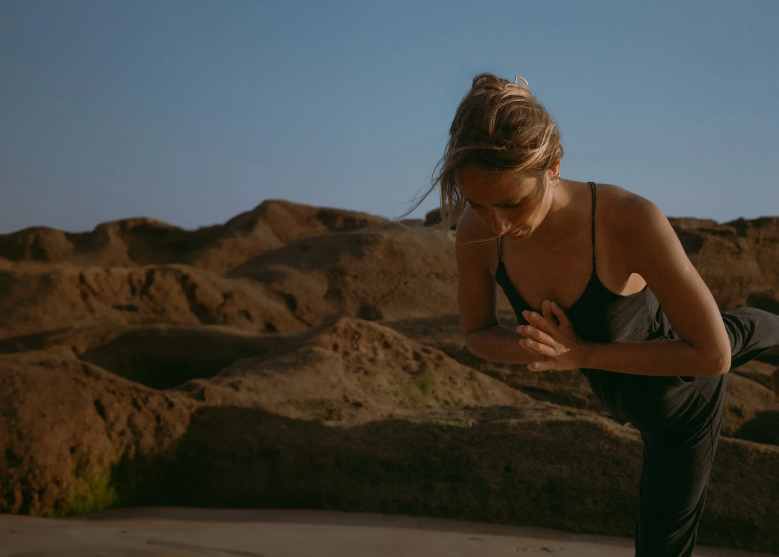 Close-Up of a Woman in Asana Posture Warrior 3. she is in nature by the ocean