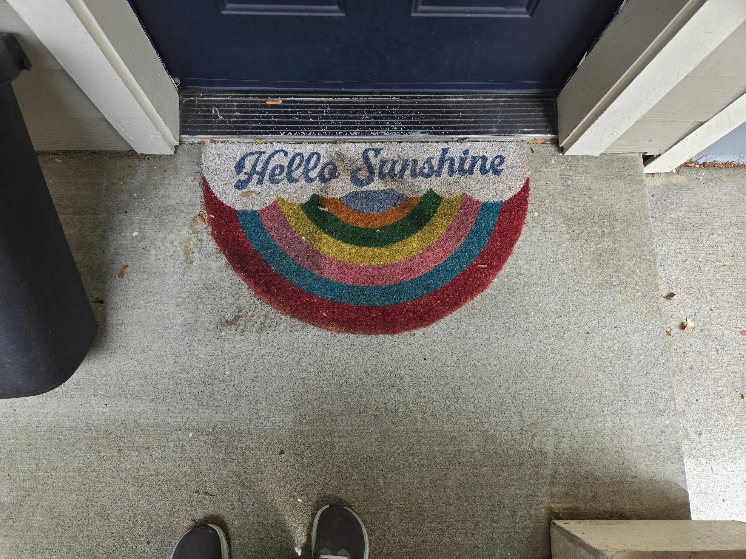 Photo of a doorstep with a welcome mat that says "hello sunshine" with a rainbow