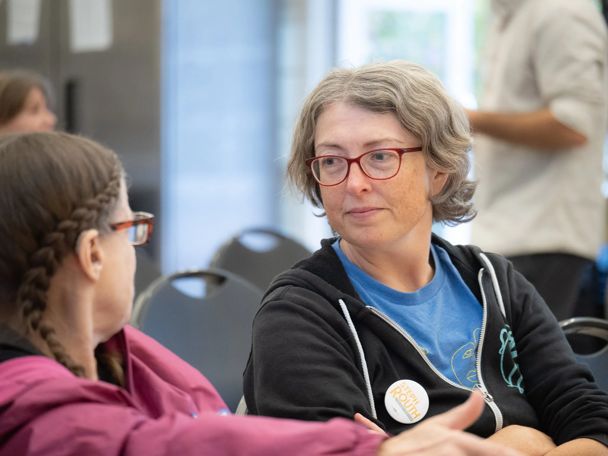 Photo of Steph sitting and listening to a constituent at a public meeting.