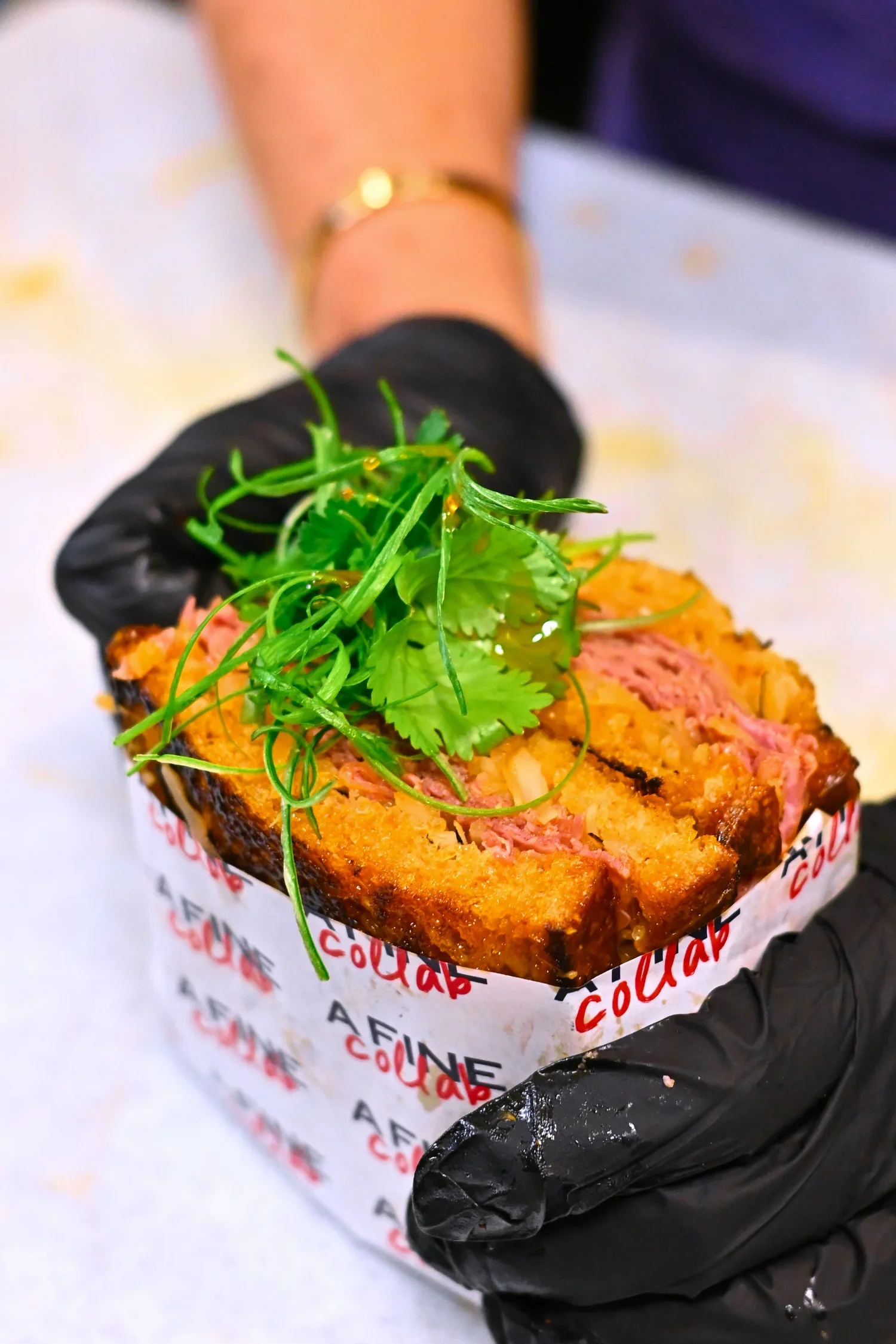 Sandwich de viande panée garni de légumes verts, servi dans une boîte en papier