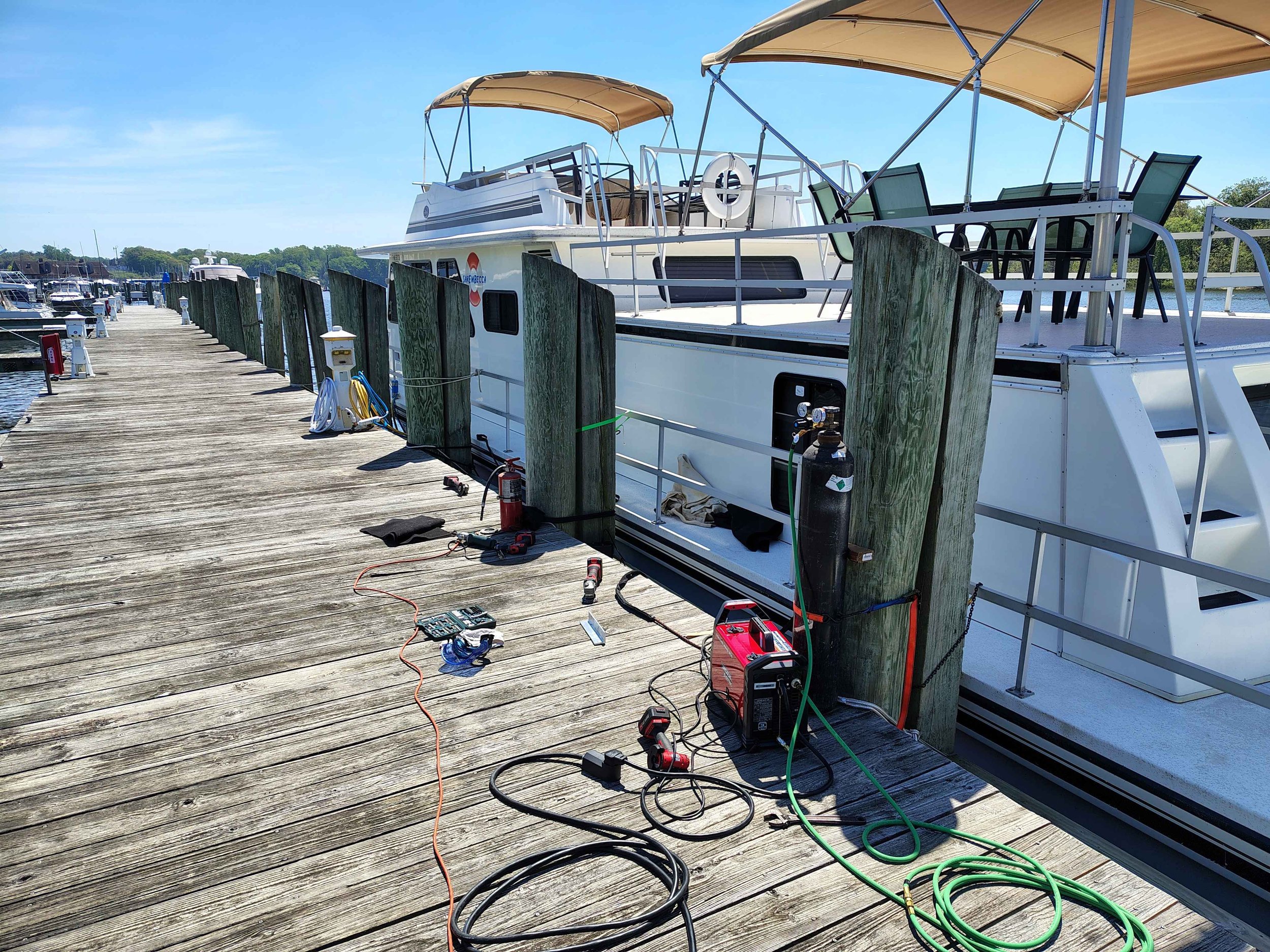 Dockside mobile aluminum welding setup alongside houseboat at marina — marine handrail and structural repair serving Chesapeake Bay region, Newark and Dover DE, PIE LLC Weld & Machine