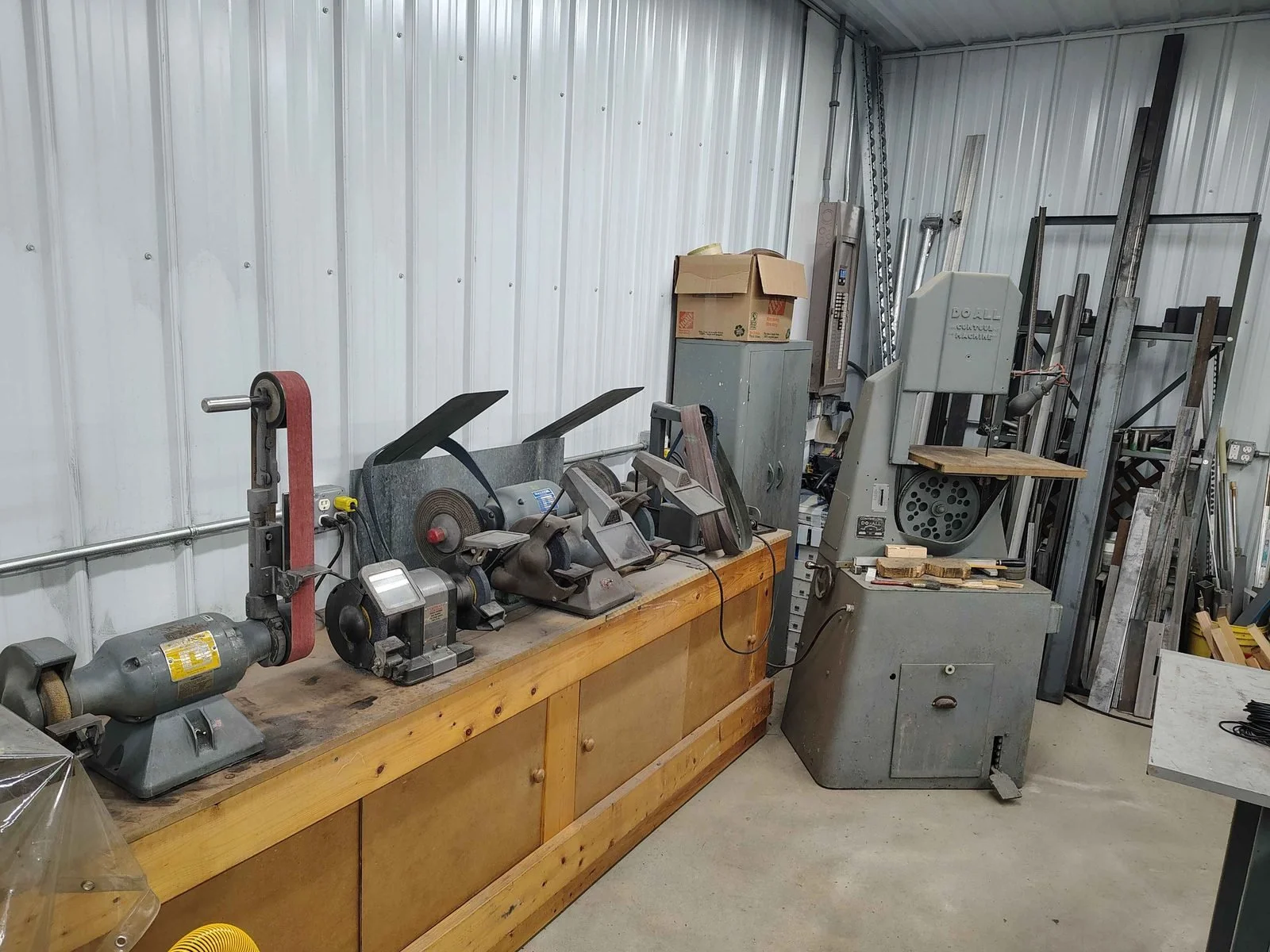 Dedicated grinding area with bench grinders, belt grinders, and a DoAll contour band saw at PIE Weld & Machine in Cecil County, MD