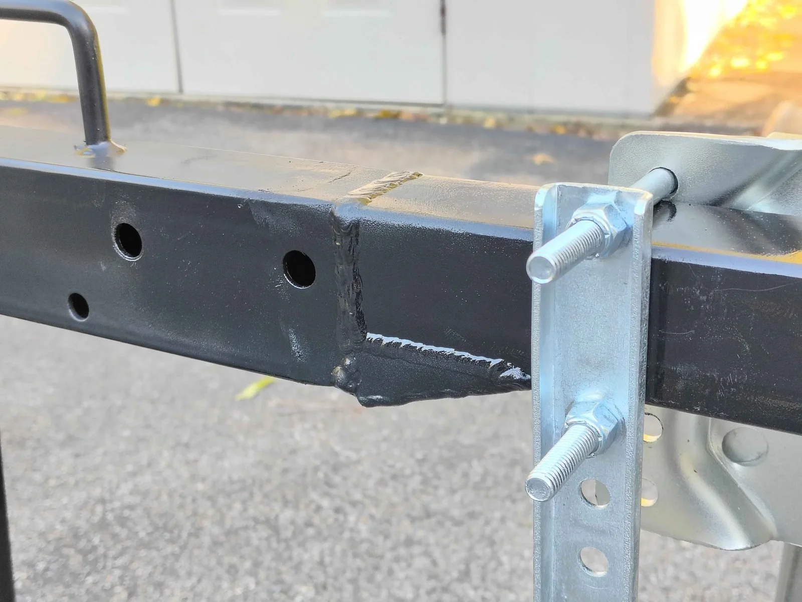 Close-up of the TIG welded 2x3 to 2x2 steel tube transition on a log splitter tongue extension, painted gloss black, by PIE Weld & Machine in Cecil County, MD