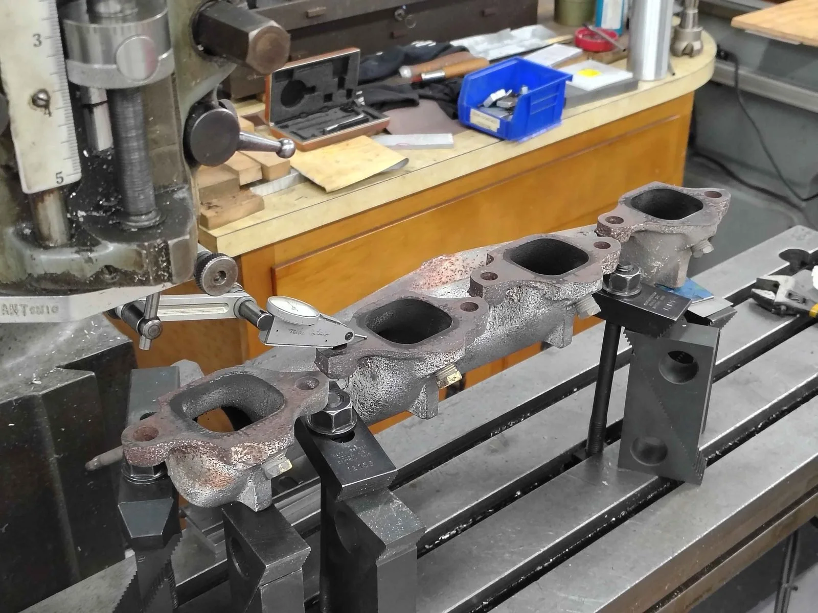 Classic 1960s Corvette cast iron exhaust manifold clamped on a Bridgeport mill and indicated for flange resurfacing at PIE Weld & Machine in Cecil County, MD