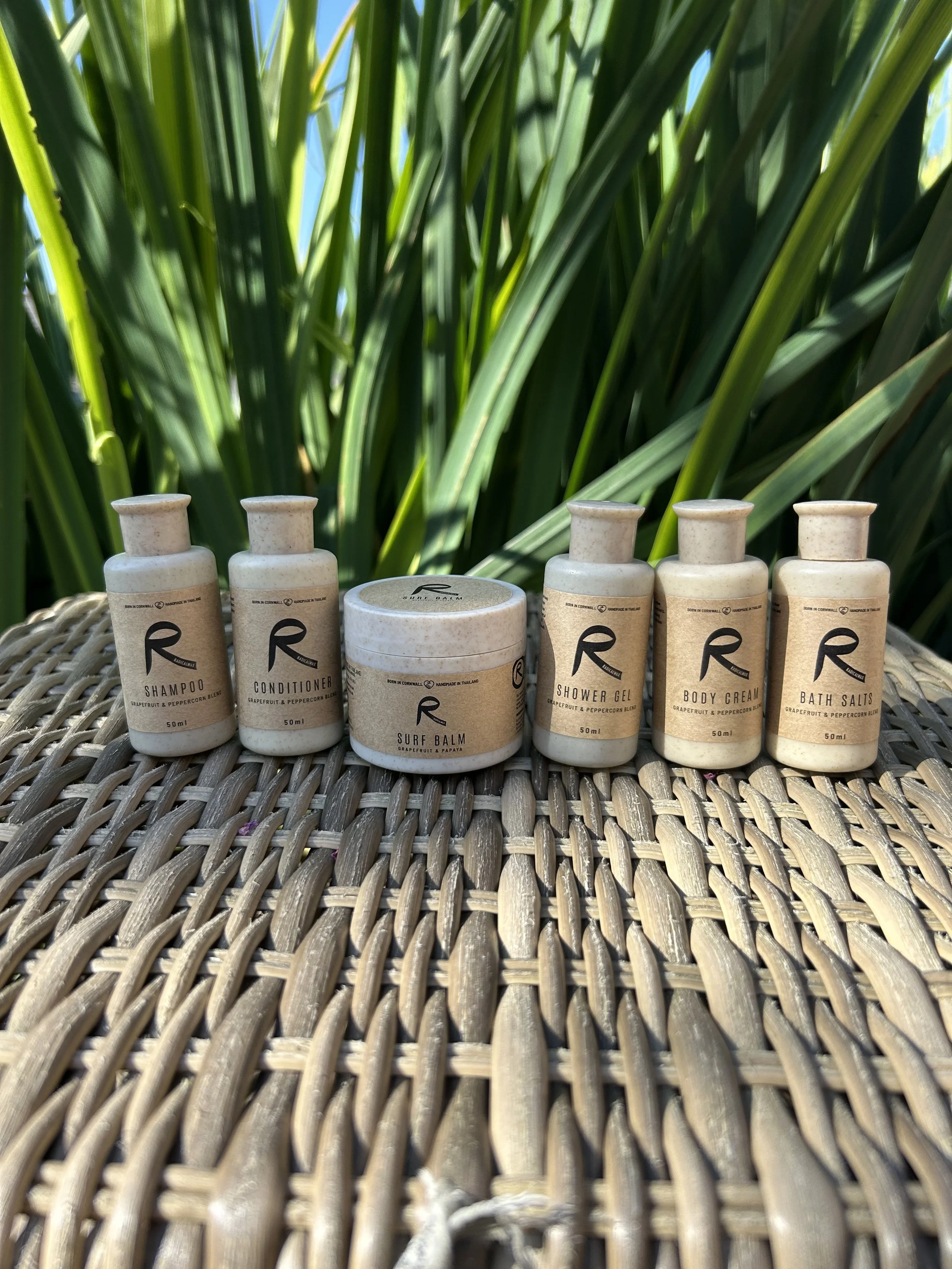Wheat bottles of personal care products with wooden caps and white 'R' logo on yellow background.