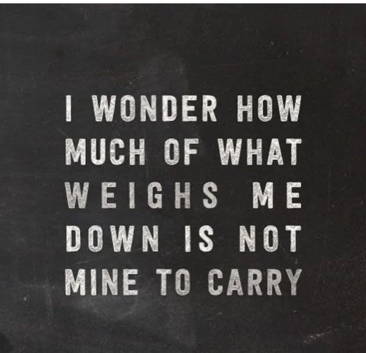 A blackboard with a motivational quote in white text that says, "I wonder how much of what weighs me down is not mine to carry."