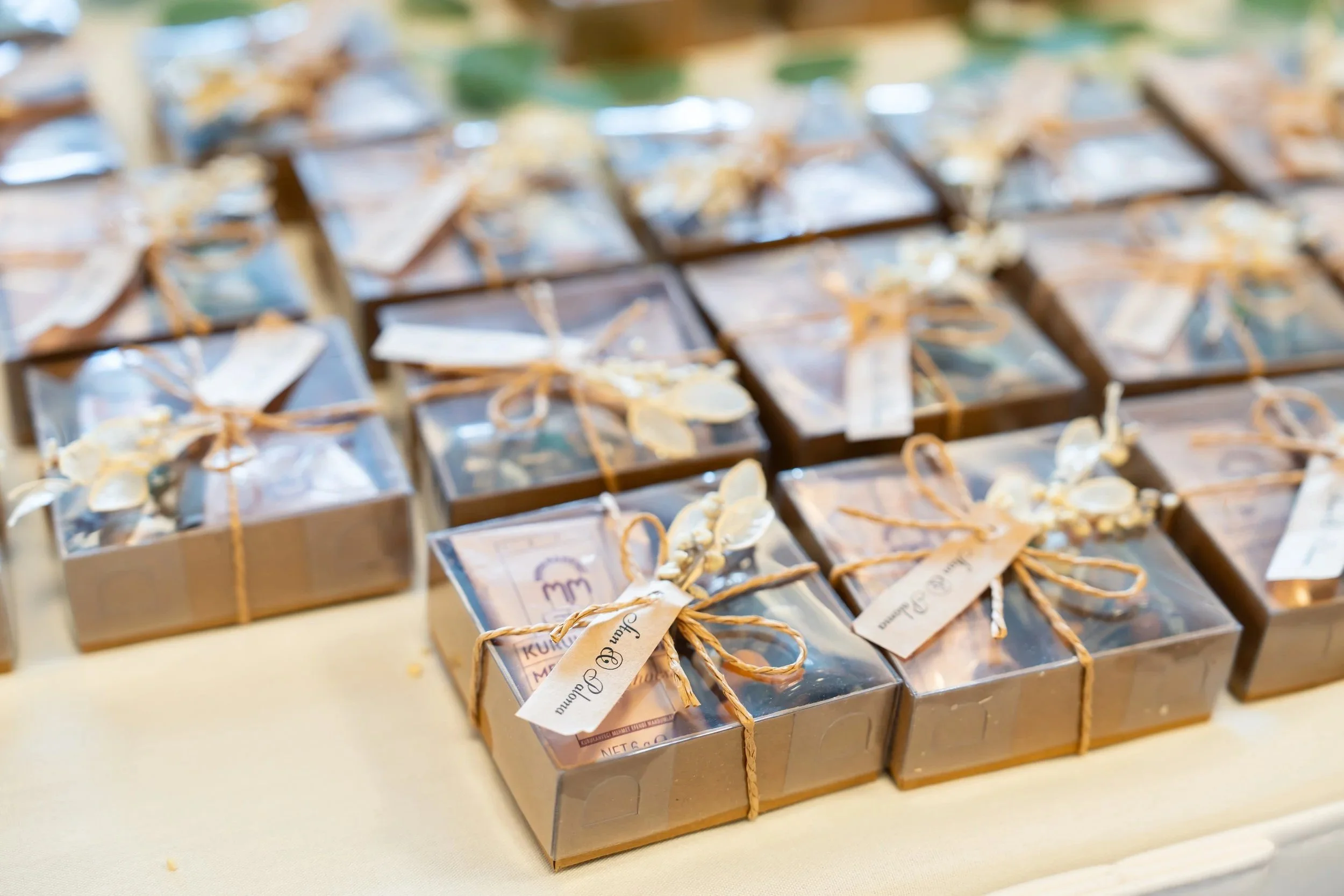 Boxes of chocolates wrapped in clear plastic and tied with string, arranged on a table.