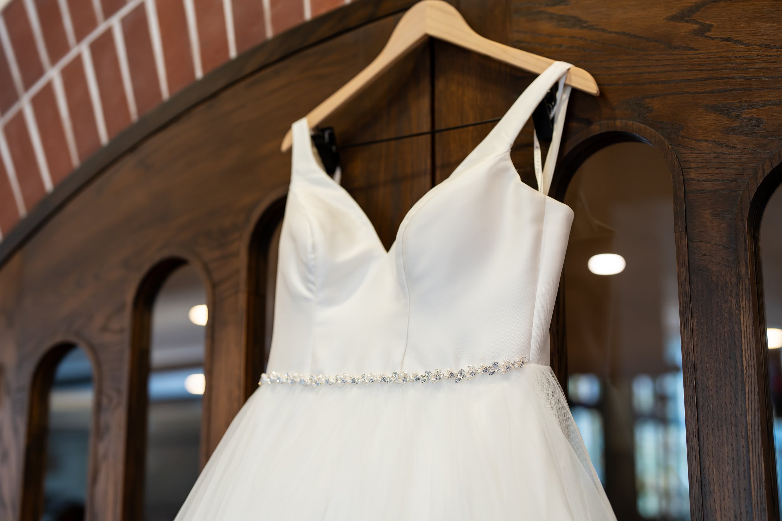Wedding dress hanging on a wooden mirror with arched mirrors