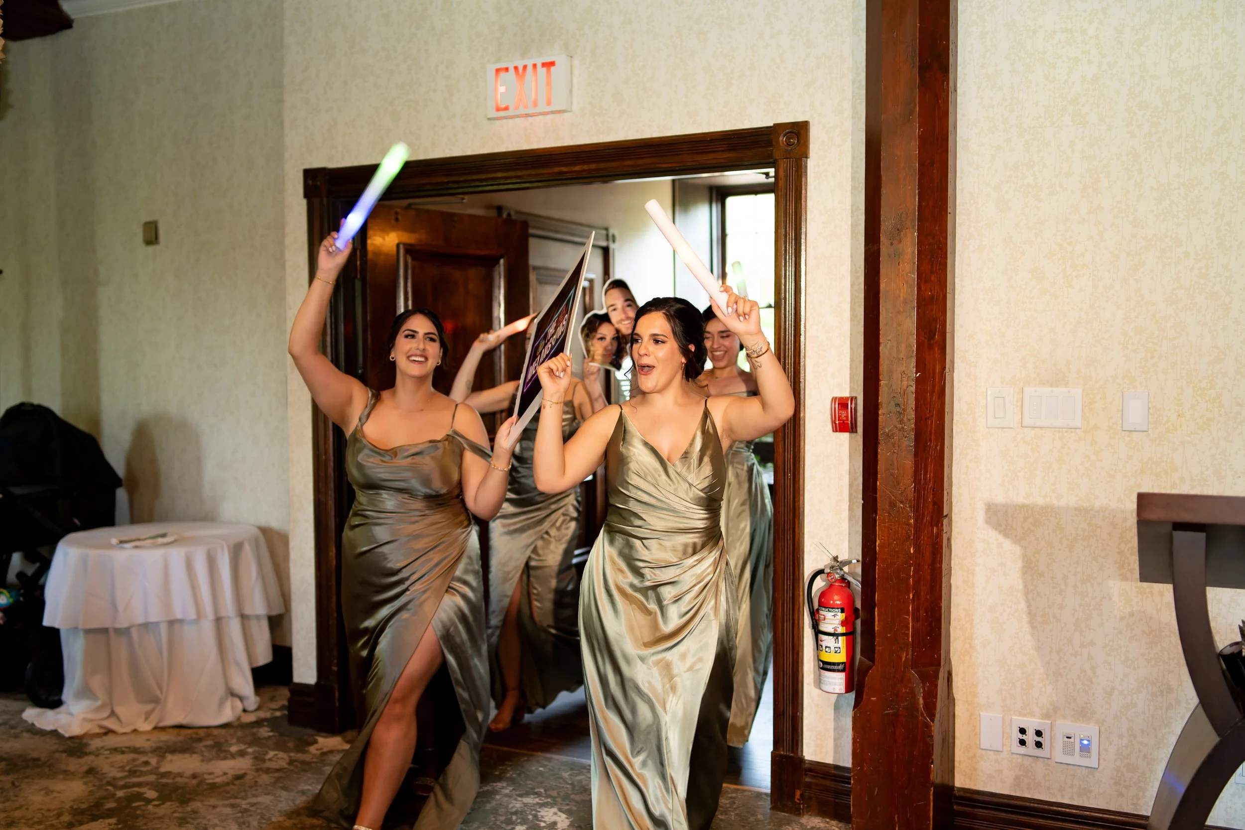 Group of women in matching gold dresses dancing with glow sticks as they enter a room.