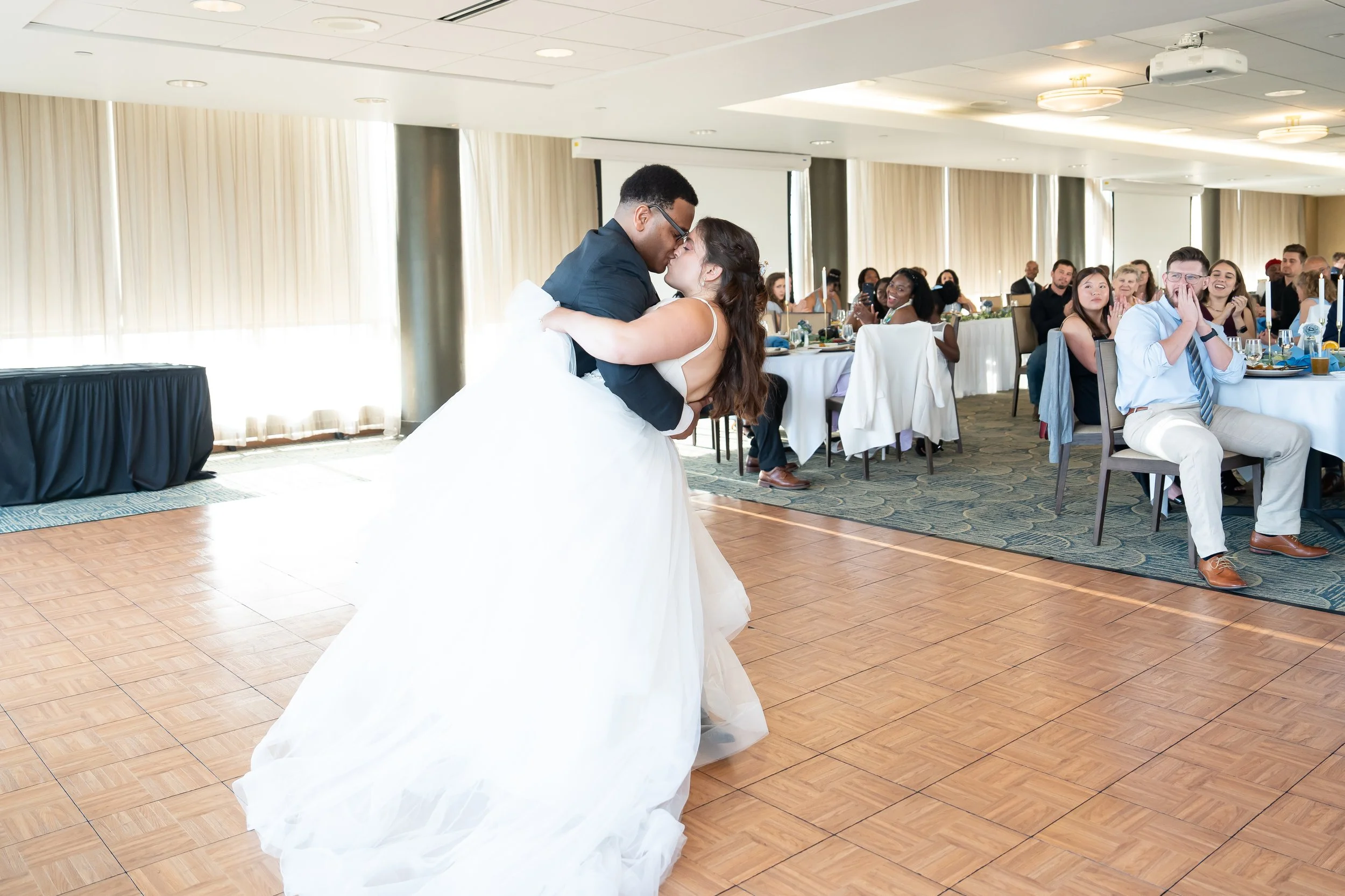 Couple dancing at wedding reception with guests watching and smiling
