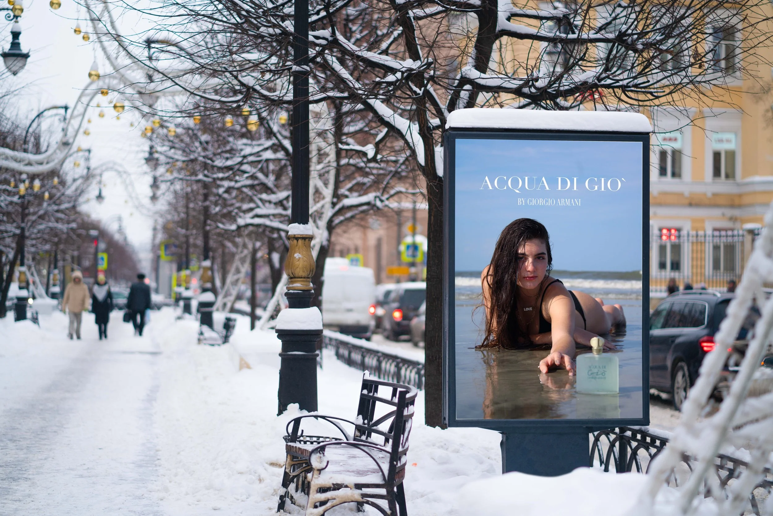 A snow-covered city street with pedestrians, parked cars, and a large poster advertisement for Giorgio Armani's Acqua di Giò featuring a woman lying on the beach.