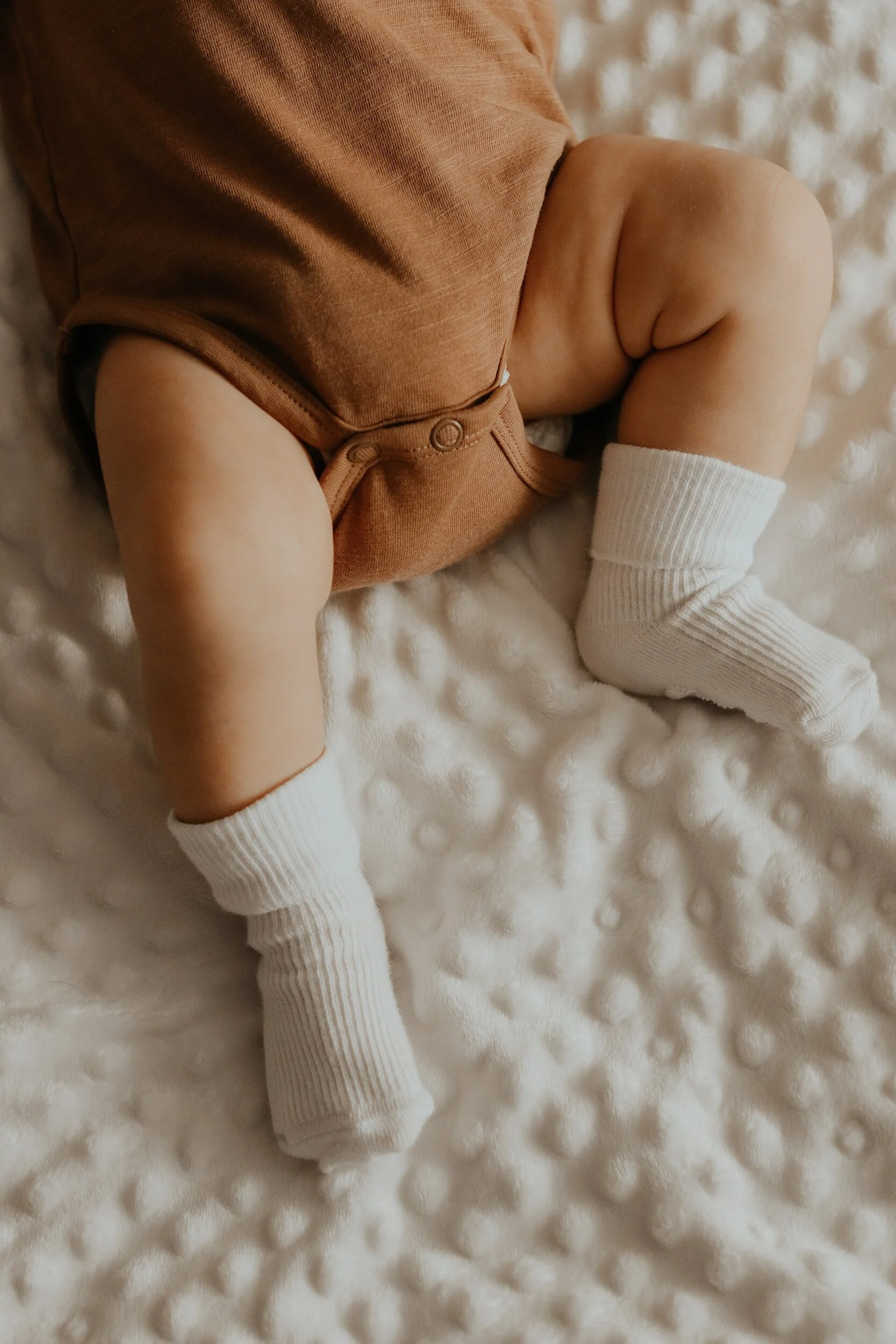 baby lying down wearing a onesie and knee high socks