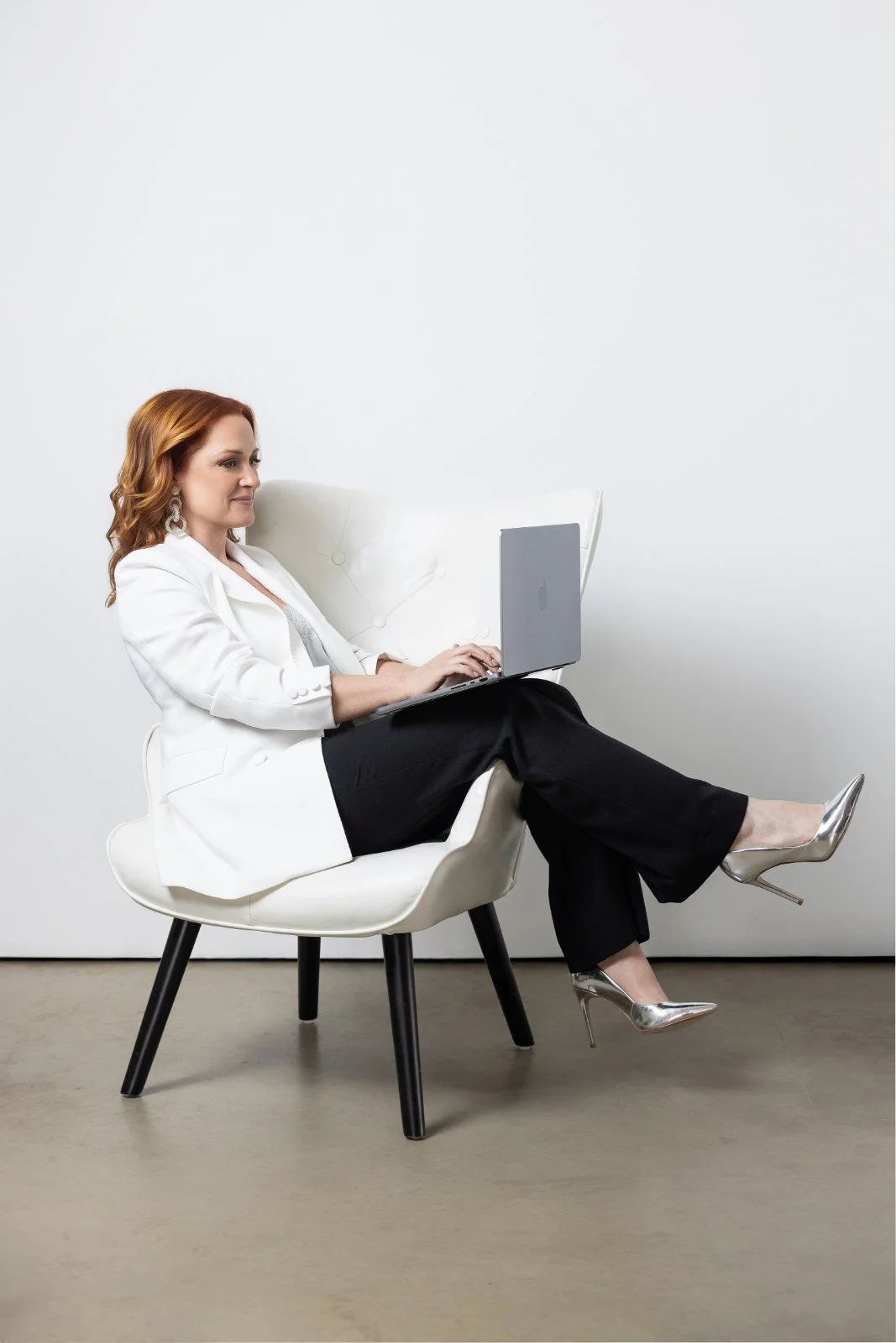 Amanda Johansen working on a laptop in a white suit