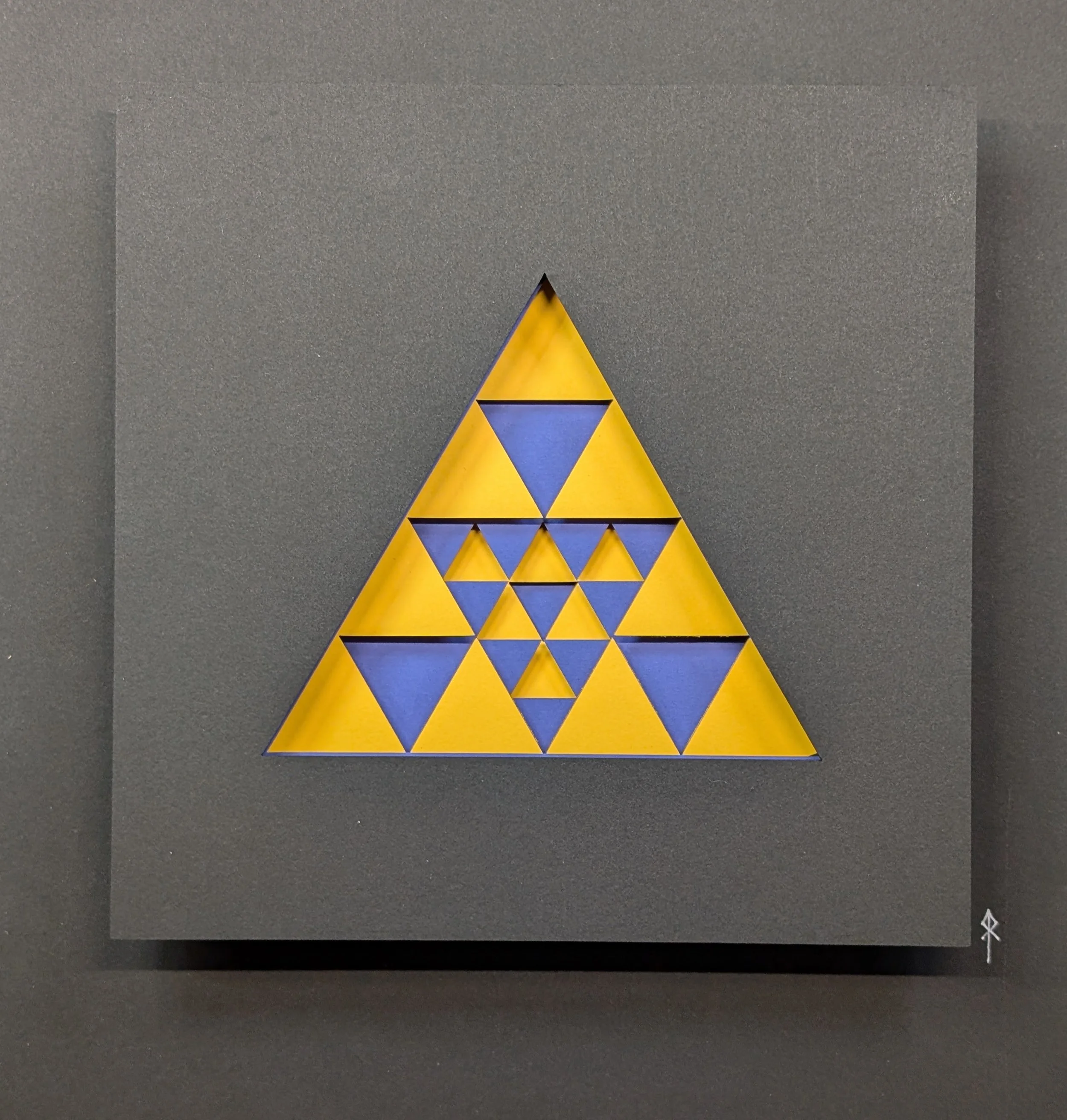 Abstract artwork featuring a large yellow triangle with smaller yellow and blue triangles arranged within it, set against a black background.