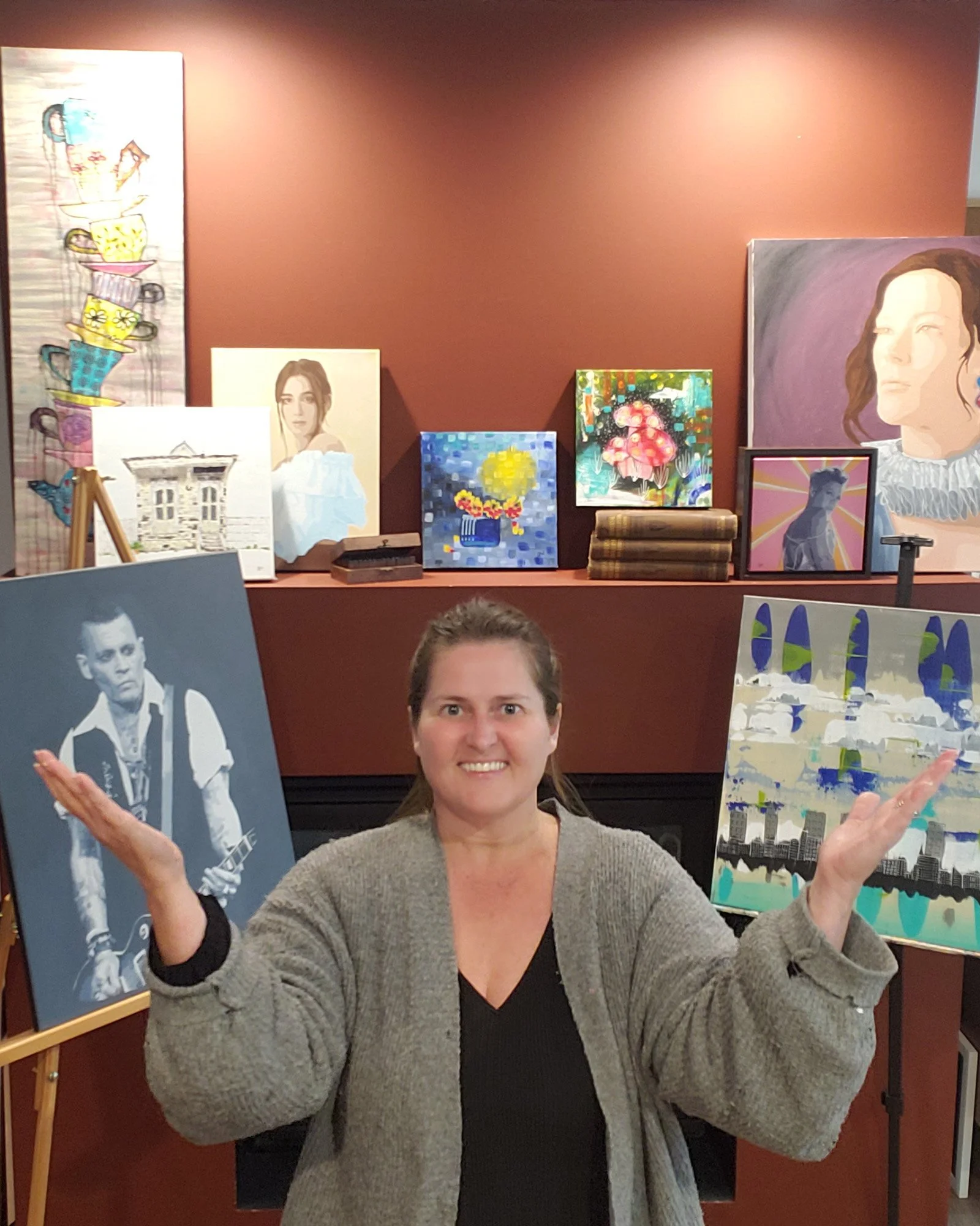 Errin is smiling at the camera with her hands up in the air indicating "look at these" 9 pieces of work.