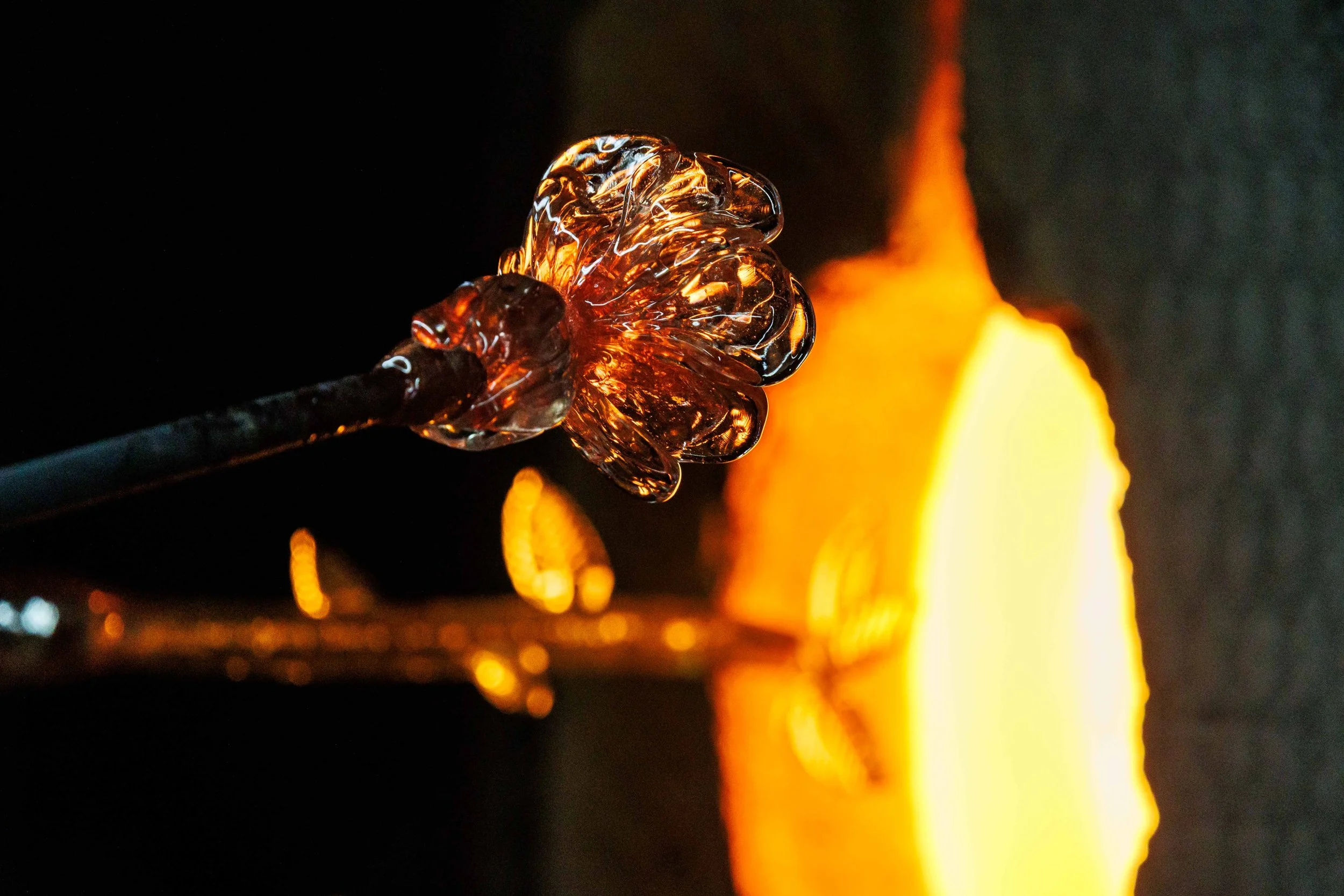  The head and stem of a glass flower by Haneul Park come out of a glory hole before being joined at the hot shop inside the Santa Monica College Art Complex. 