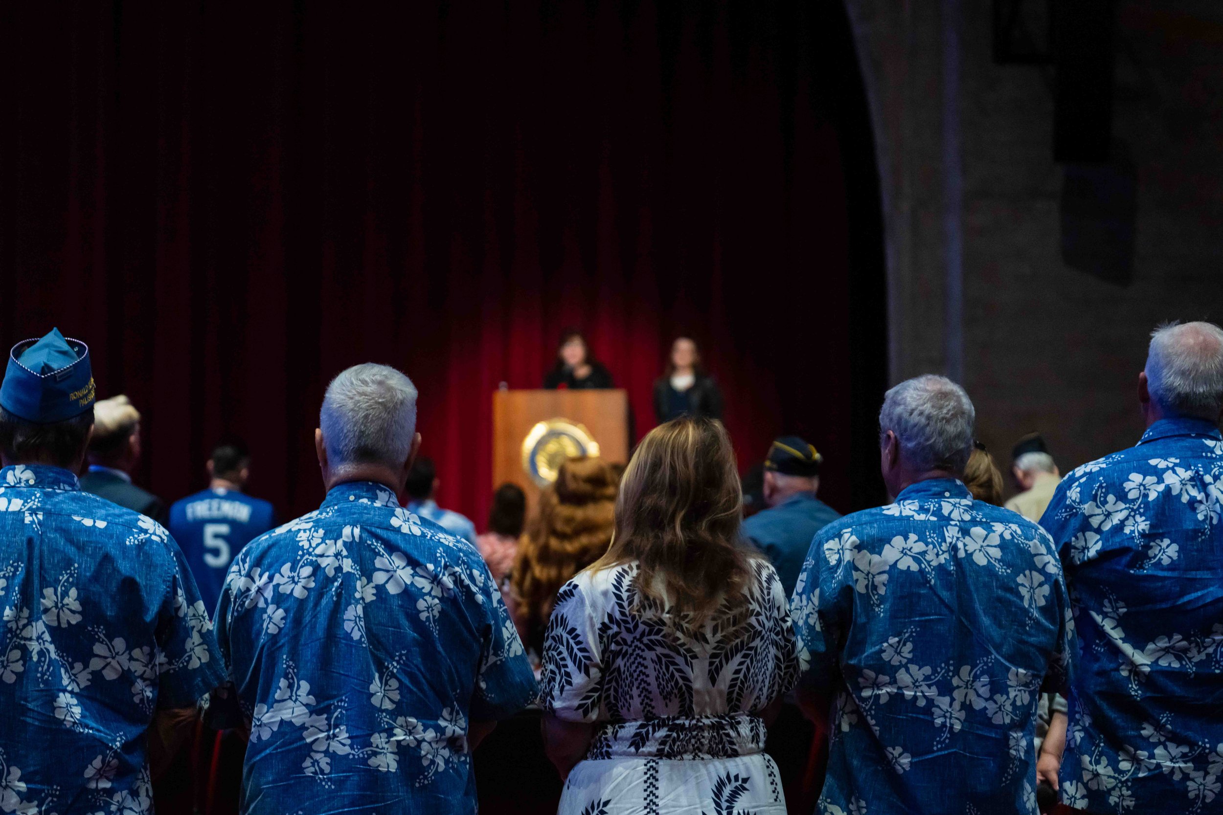  Sons of the American Legion stand in flowered blue shirts while Martha Romano speaks. 