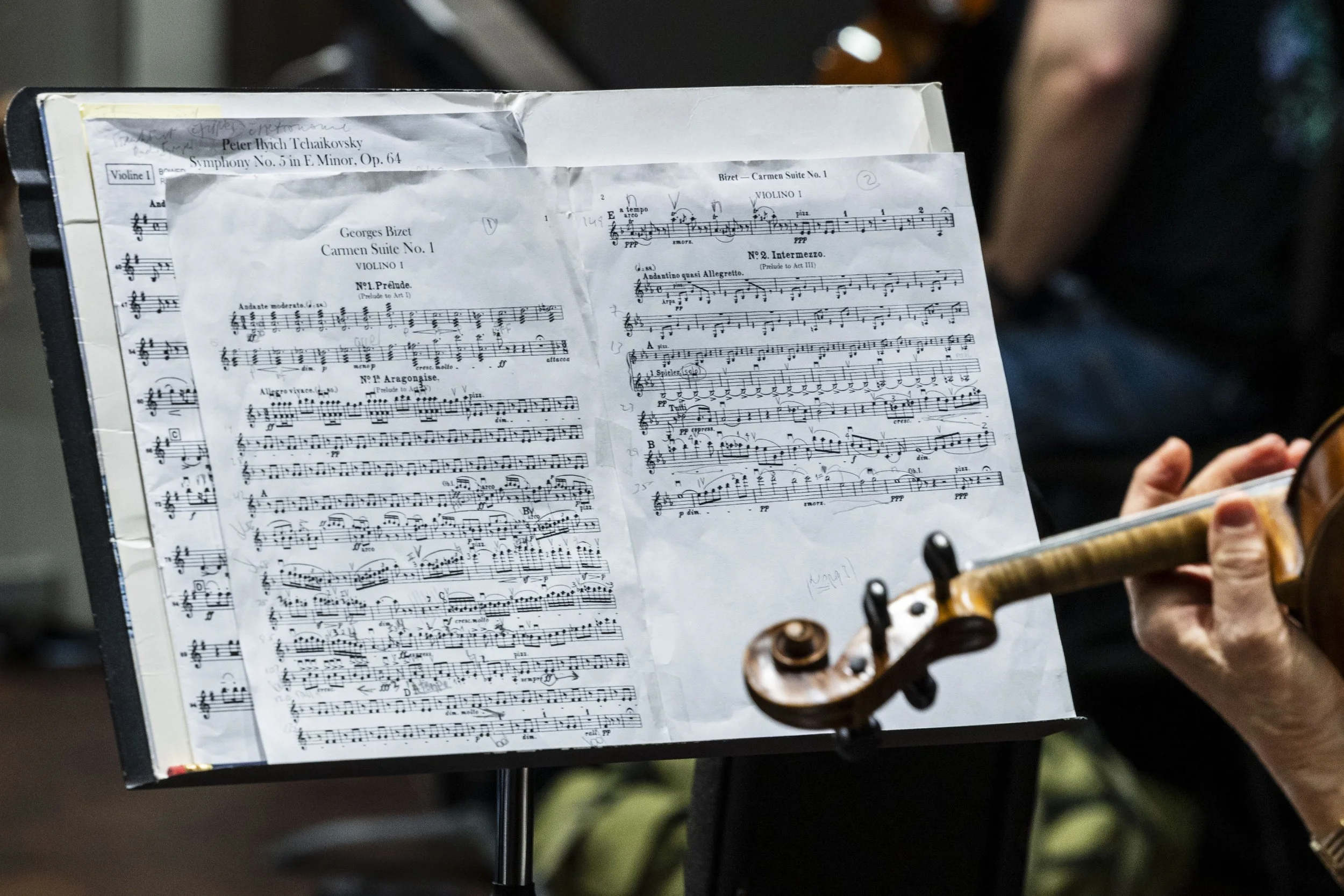 Sheet music for a violin piece with a person playing a violin in the background.