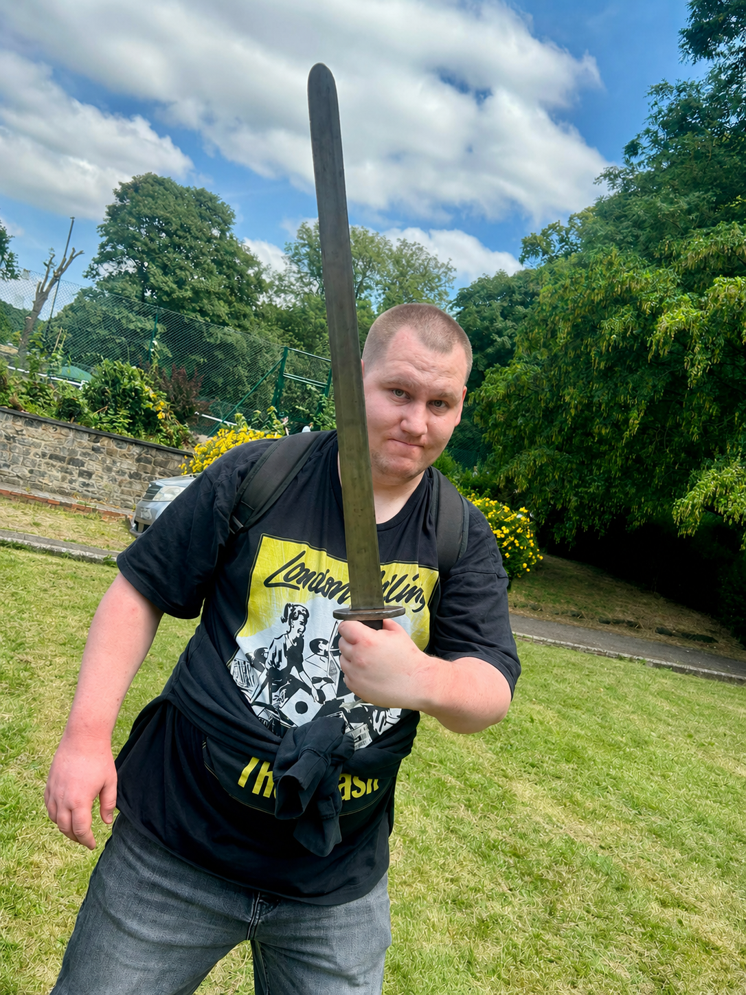 Generated image_ Man with sword in park setting.png