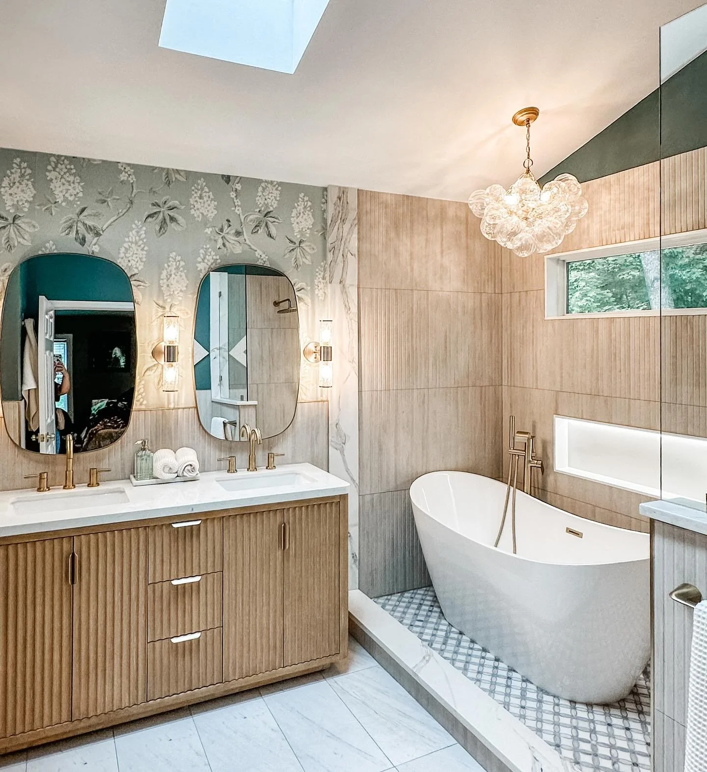 What was once a dull, uninspired bathroom is now a tranquil spa oasis for my client. We brought her dream retreat to life with a soaking tub for ultimate relaxation, statement lighting that sets the mood, and a wallpaper accent wall that steals the s