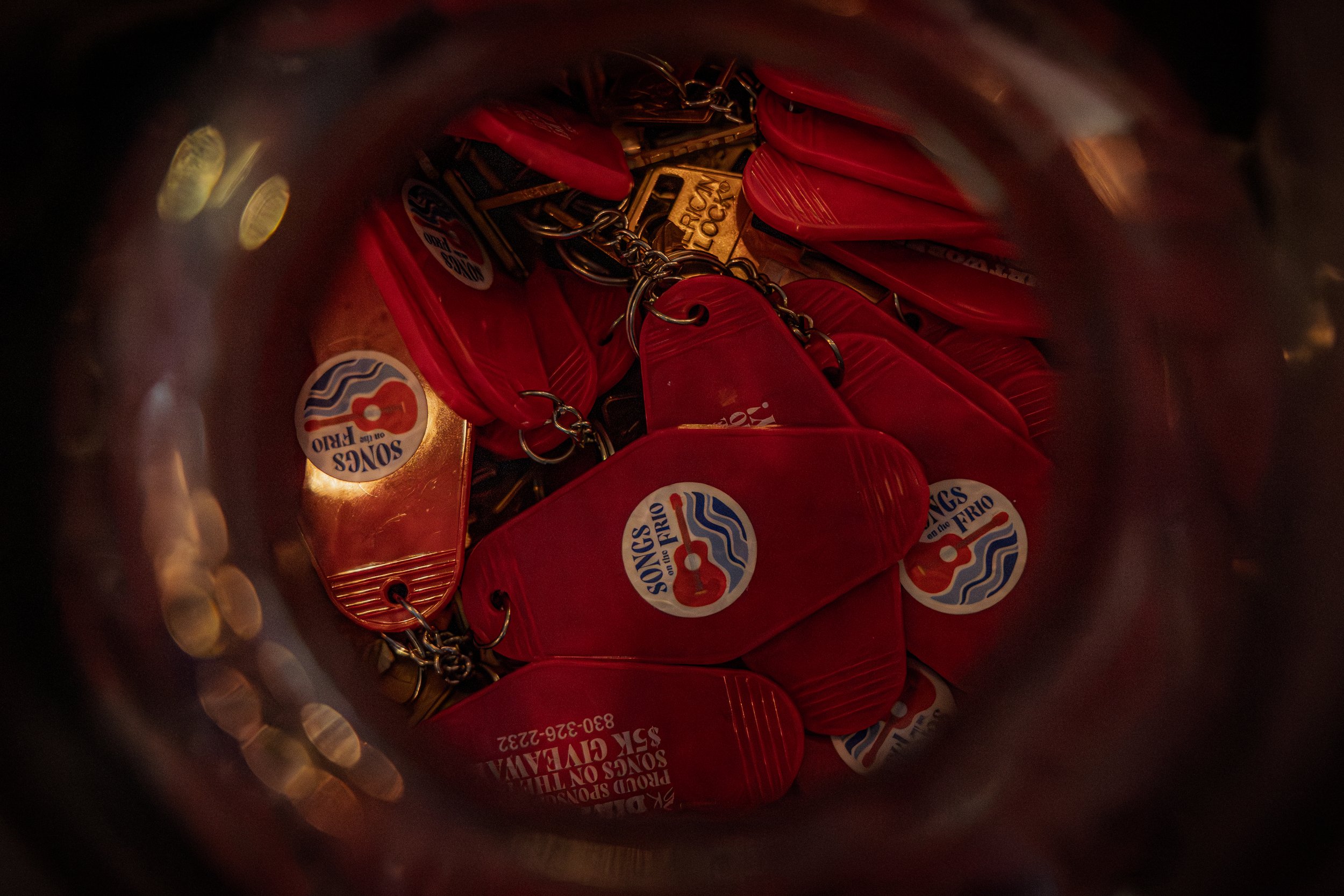 A collection of red buttons with a 'Songs on the Frio' sticker inside a metallic container.